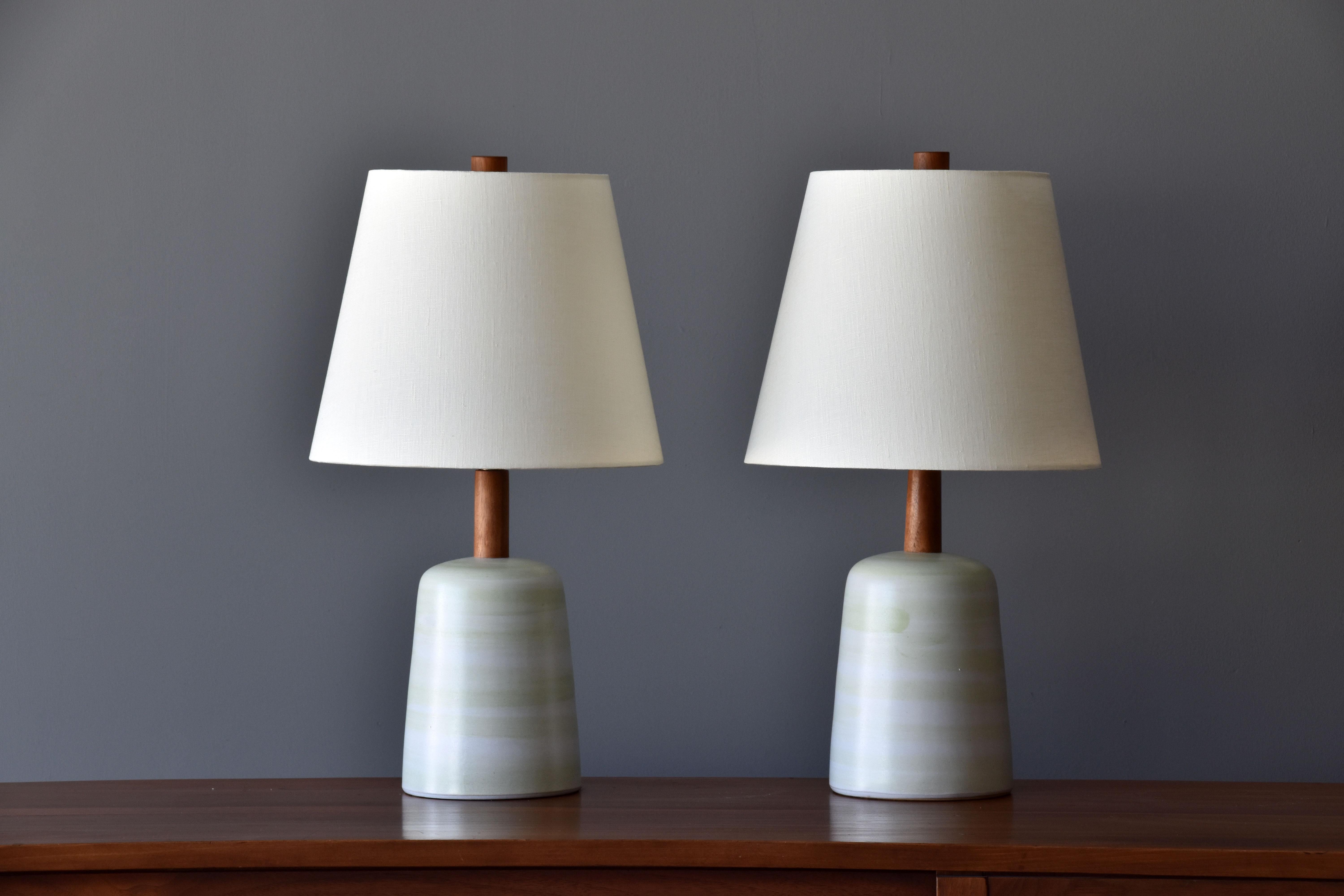 A pair of table lamps designed by husband and wife duo Jane & Gordon Martz. Produced by Marshall Studios, Indianapolis. 

Bases are slip-cast and then dipped into glaze. Design also incorporates exquisite walnut necks and finials. Bases are
