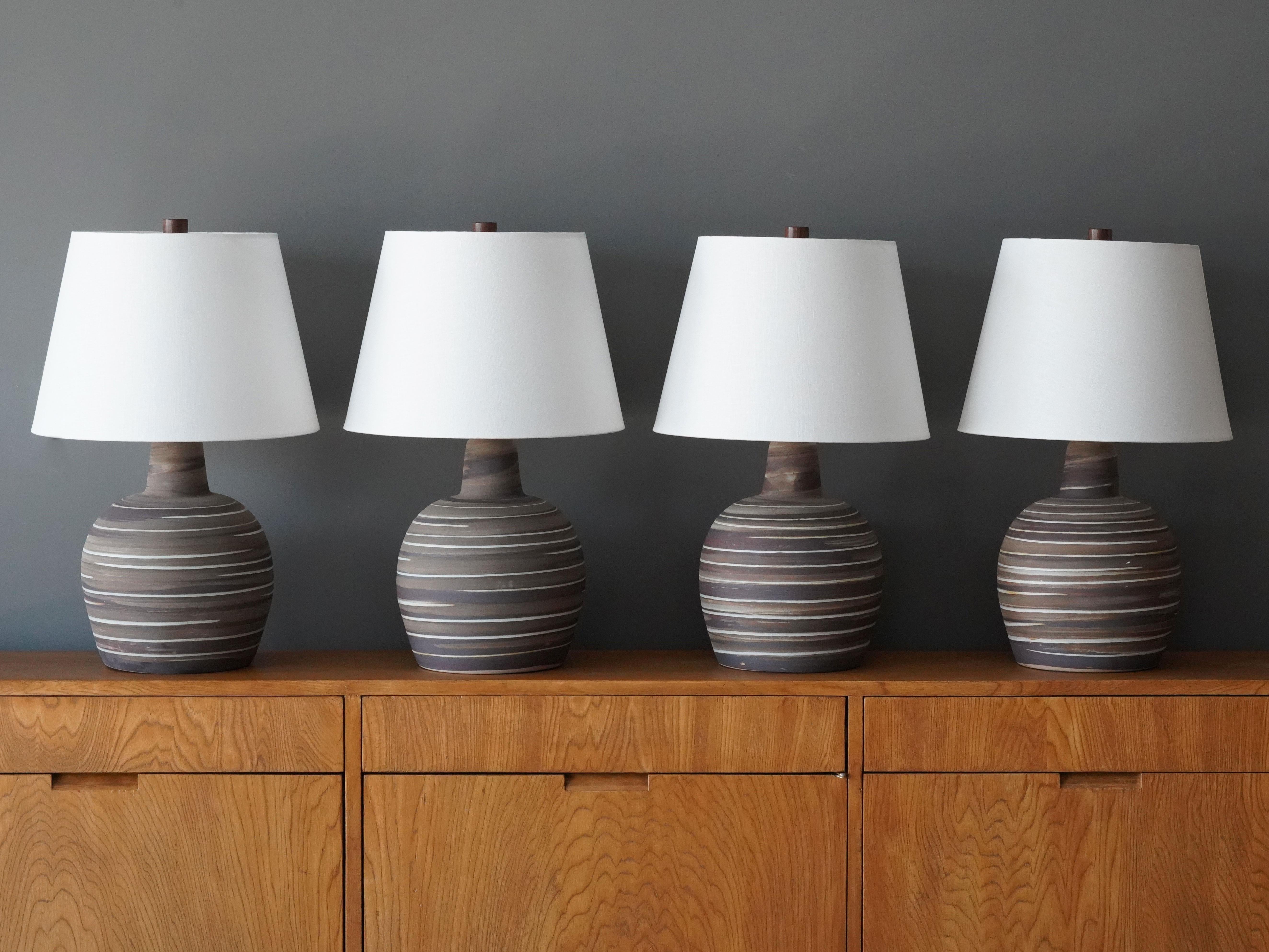 A pair of table lamps designed by husband and wife duo Jane & Gordon Martz. Produced by Marshall Studios, Indianapolis. 

Bases are slip-cast and then dipped into glaze and hand painted. Design also incorporates exquisite walnut necks and finials.