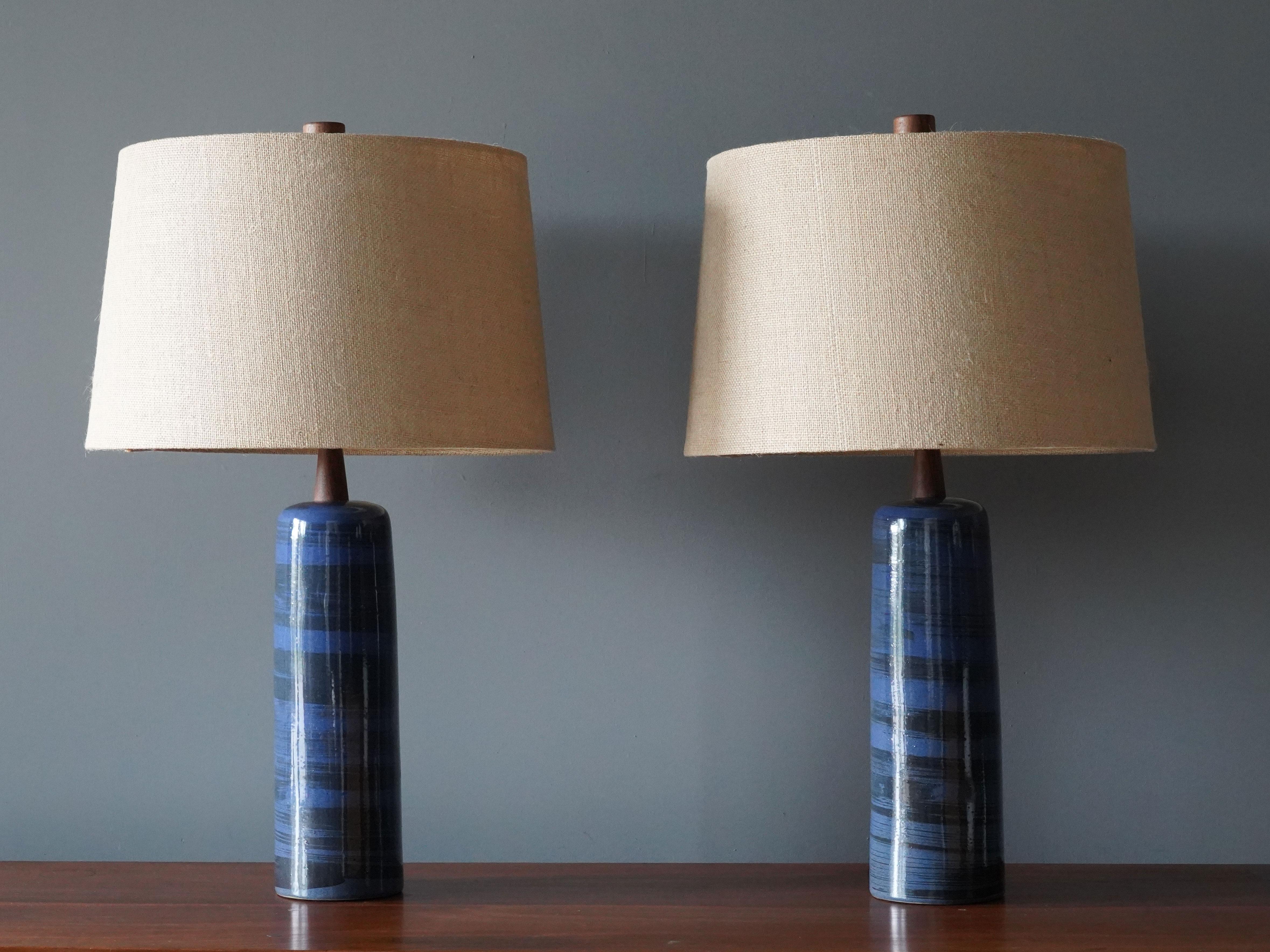 A pair of table lamps designed by husband and wife duo Jane & Gordon Martz. Produced by Marshall Studios, Indianapolis. 

The blue bases are slip-cast and then dipped into glaze and hand painted. Design also incorporates exquisite walnut necks and