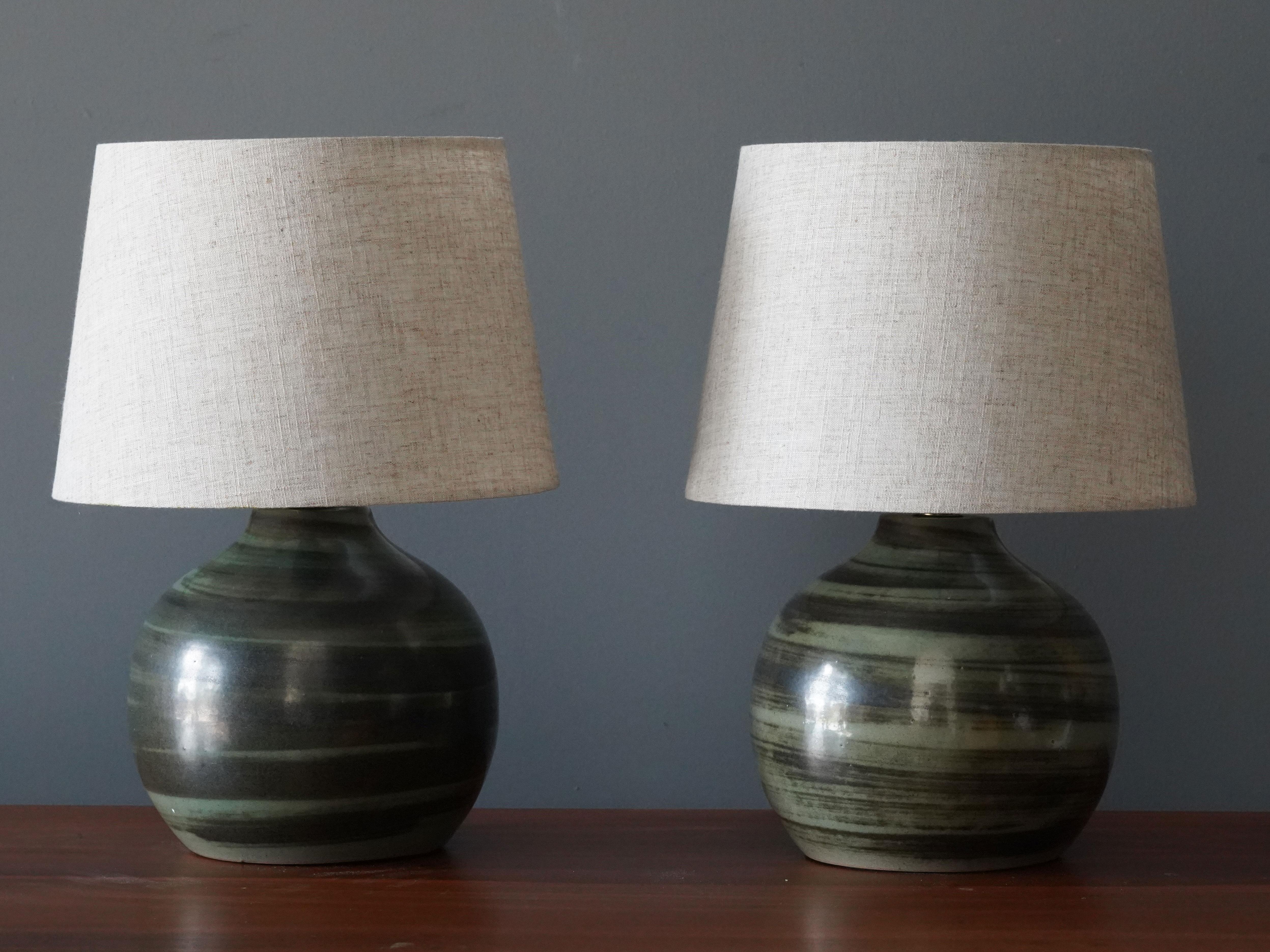 A pair of table lamps designed by husband and wife duo Jane & Gordon Martz. Produced by Marshall Studios, Indianapolis. 

The olive green bases are slip-cast and then dipped into glaze and hand painted. Bases are signed.

Jane & Gordon Martz