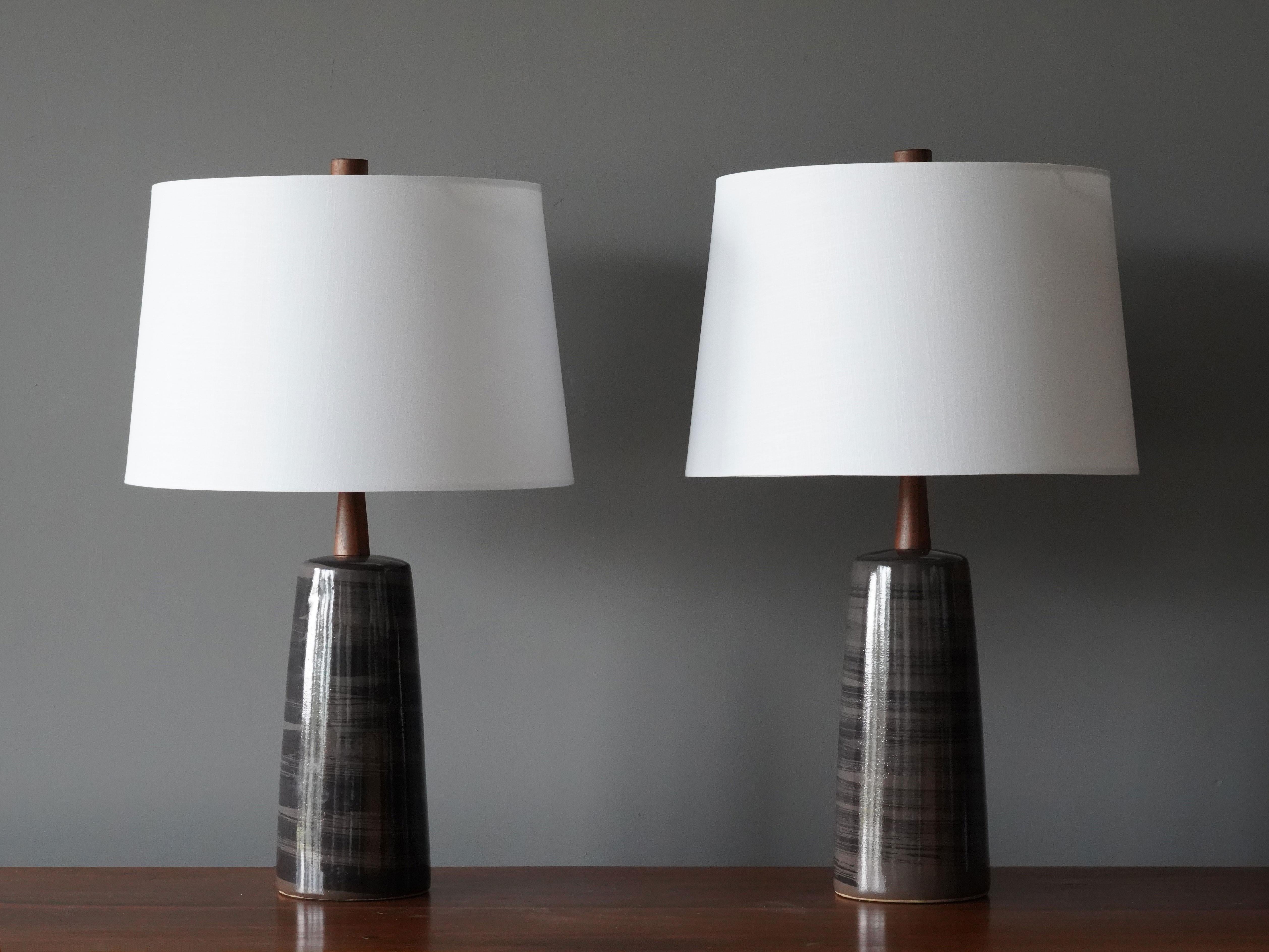 A pair of table lamps designed by husband and wife duo Jane & Gordon Martz. Produced by Marshall Studios, Indianapolis. 

The bases are slip-cast and then dipped into glaze and hand-painted. Design also incorporates exquisite walnut necks and