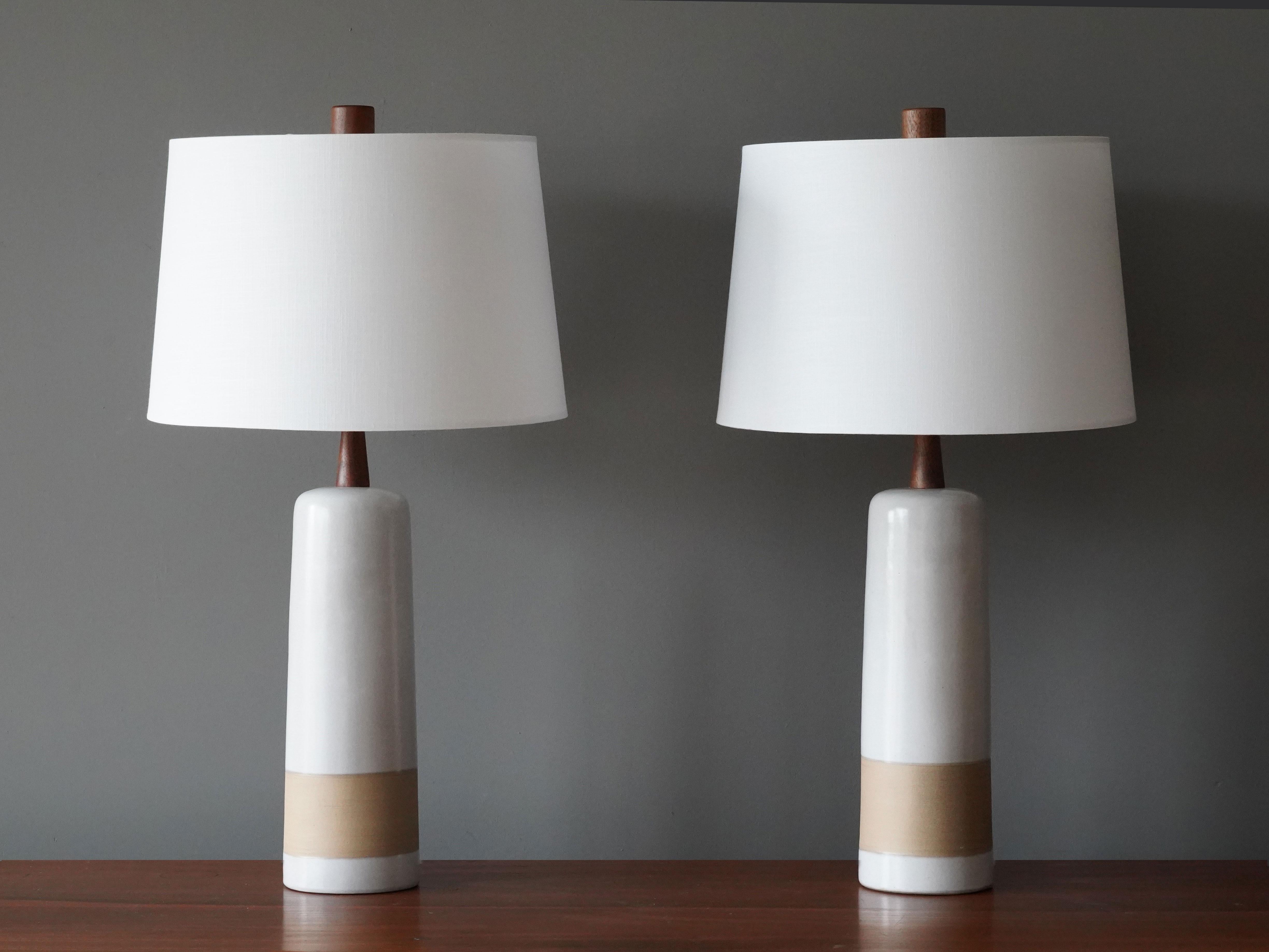 A pair of table lamps designed by husband and wife duo Jane & Gordon Martz. Produced by Marshall Studios, Indianapolis. 

The white / beige bases are slip-cast and then dipped into glaze and hand-painted. Design also incorporates exquisite walnut