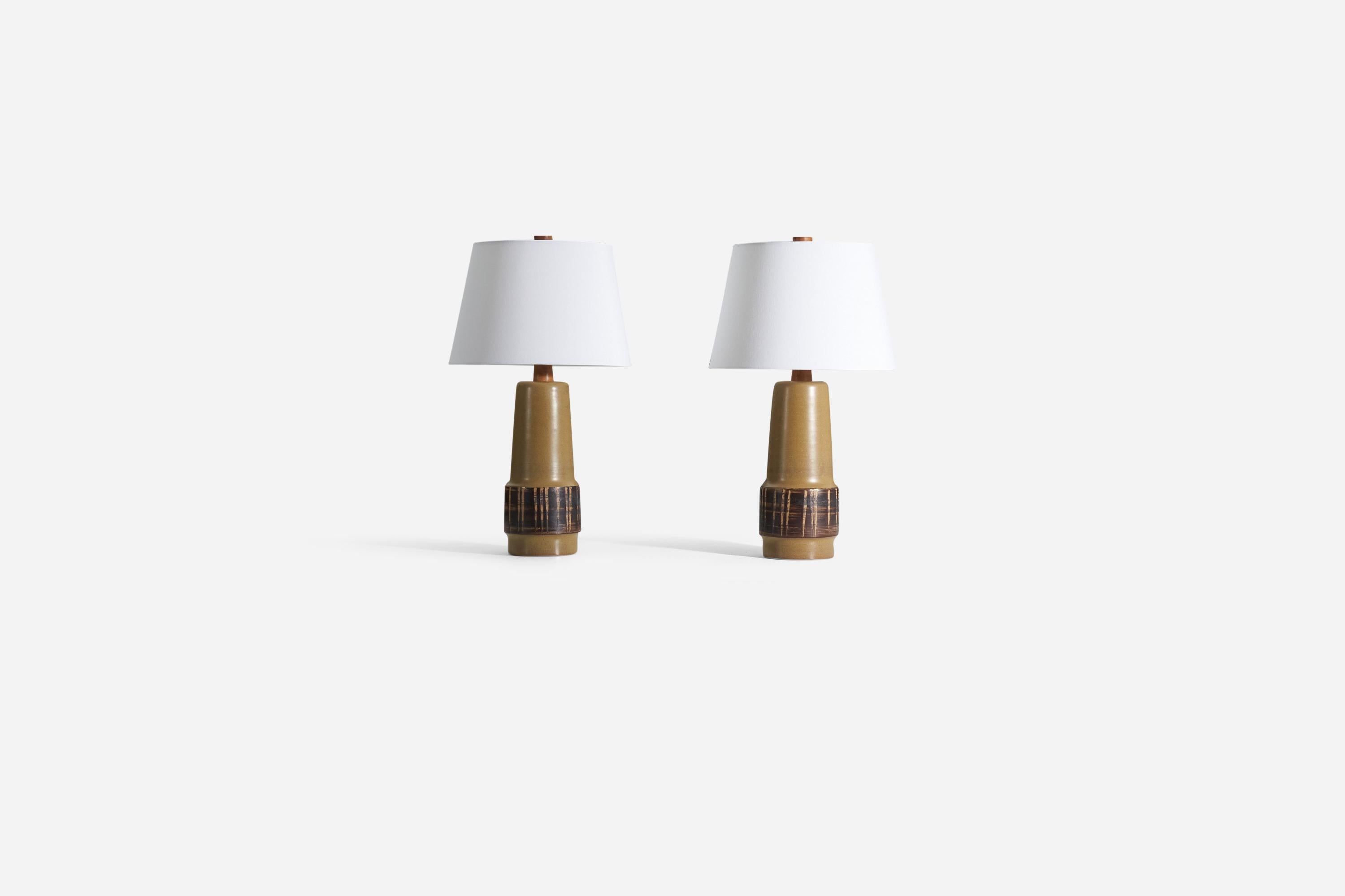 A pair of table lamps designed by husband and wife duo Jane & Gordon Martz. Produced by Marshall Studios, Veedersburg, Indiana. The base is slip-cast and then dipped into glaze and hand-painted. The design also incorporates an exquisite walnut neck