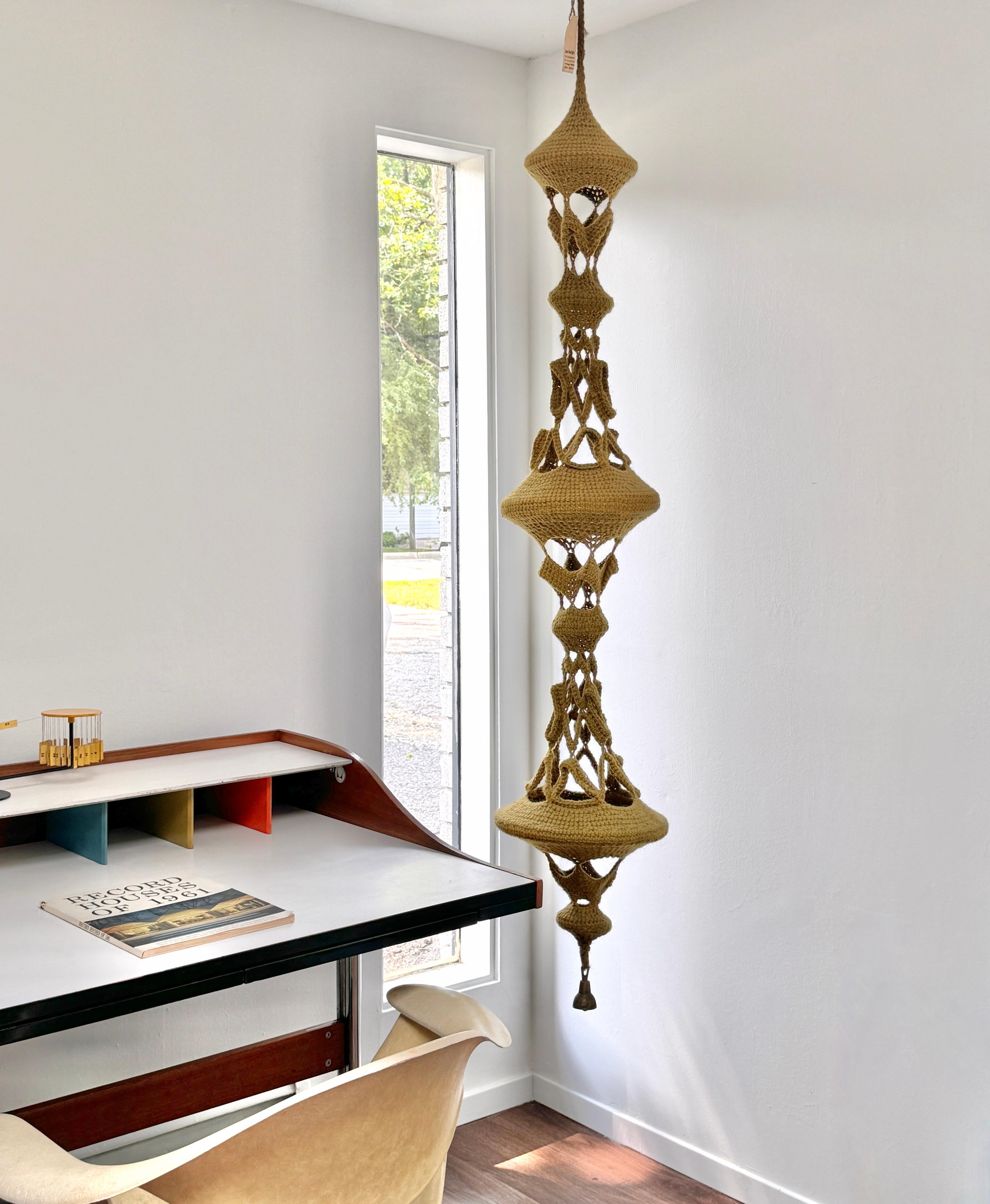 Suspended macrame sculpture by Michigan fiber artist Jane Knight circa 1970s

Three dimensional open weave crocheted sculpture in a muted chartreuse wool, adorned with a hanging brass chime

From the artist's personal collection

12 inch diameter at