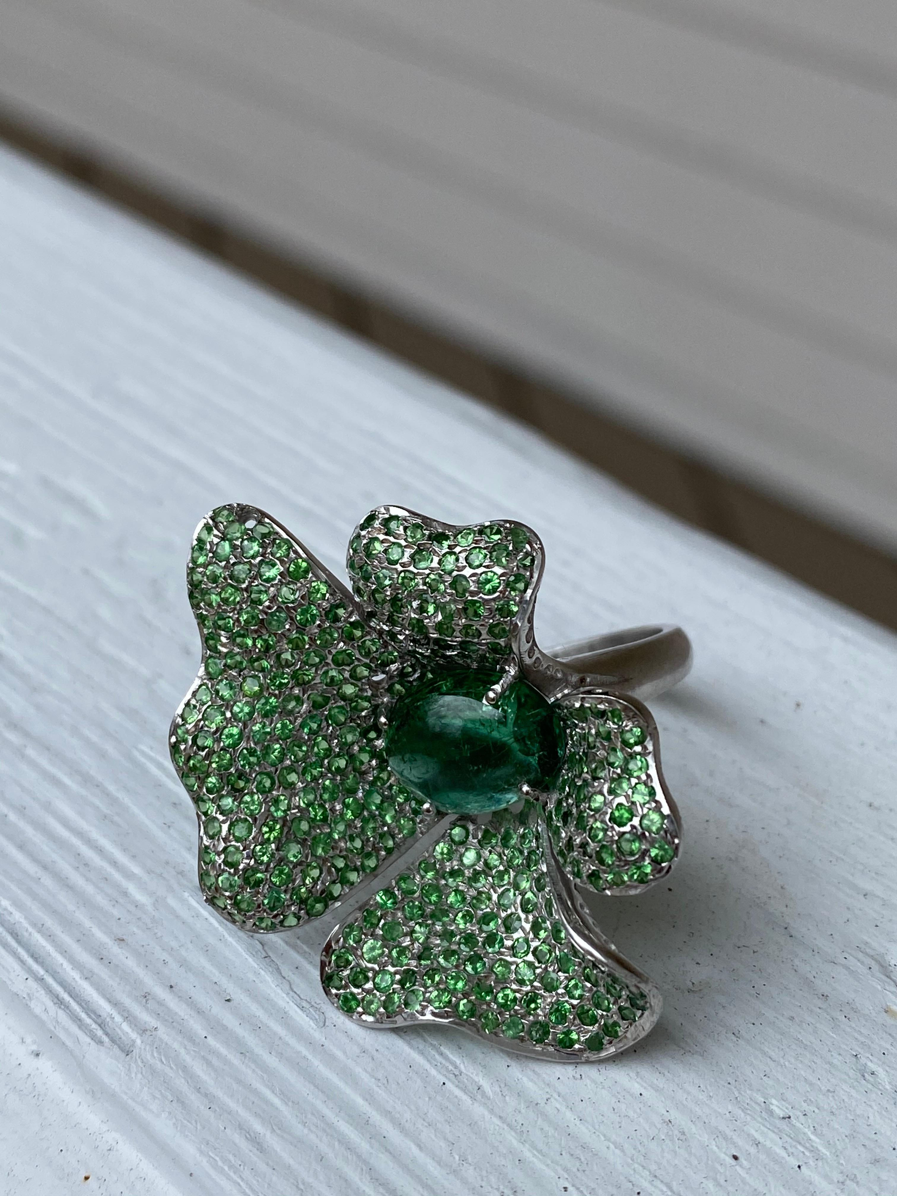 This is a unique ring with an 11x9 oval Green Tourmaline weighing approximately 3.50cts with pave set Green Tsavorite Garnets set in Rhodium Plated Sterling Silver. 
Finger size just under 6.5 for US finger size. The Hardness of this gemstone is 7