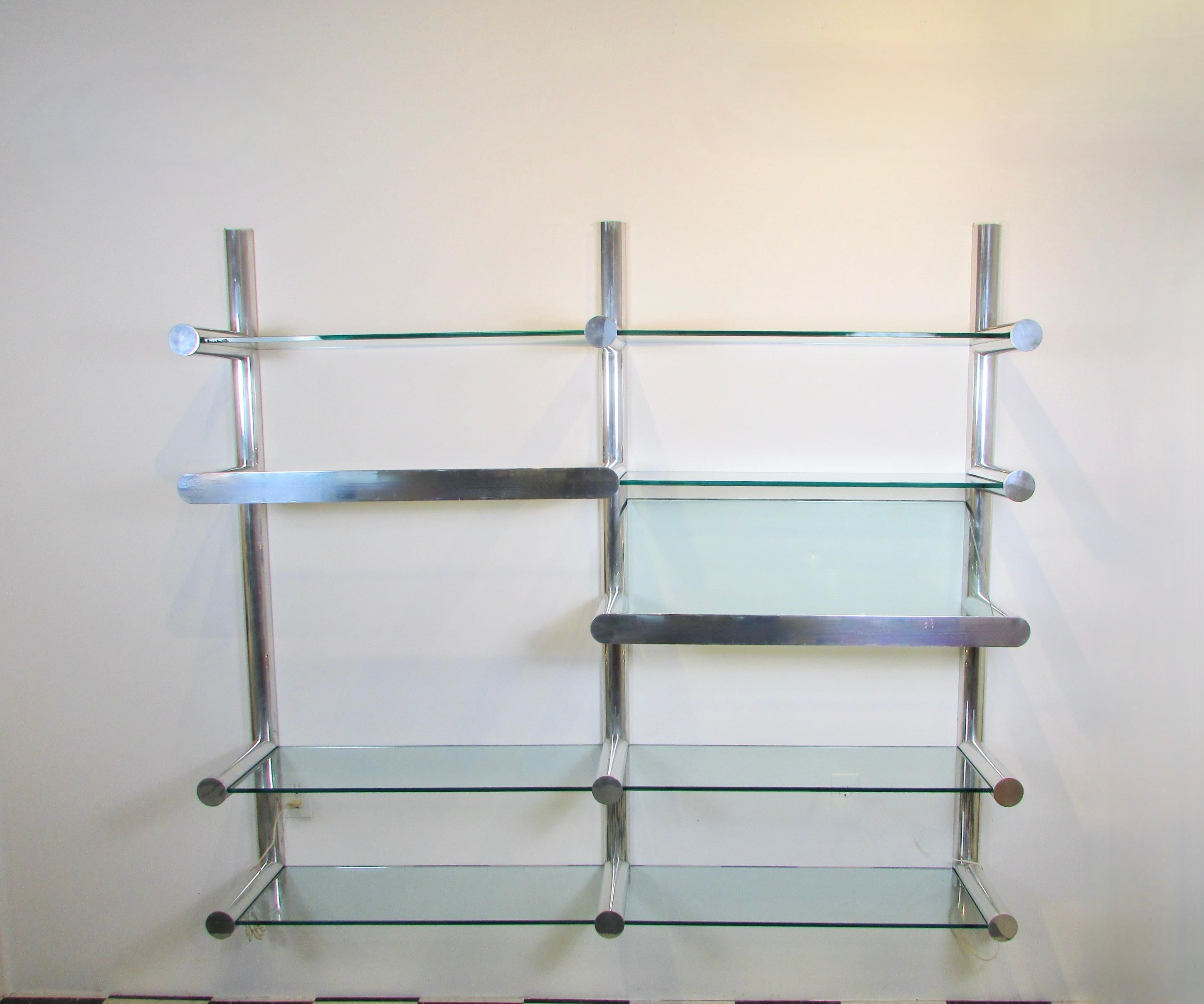 Impressive wall system of extruded polished aluminum half cylinder uprights with full cylindrical horizontal arms extending to hold 7 half inch thick glass shelves and one angle shelf for art, book or magazine display. The 3' diameter aluminum