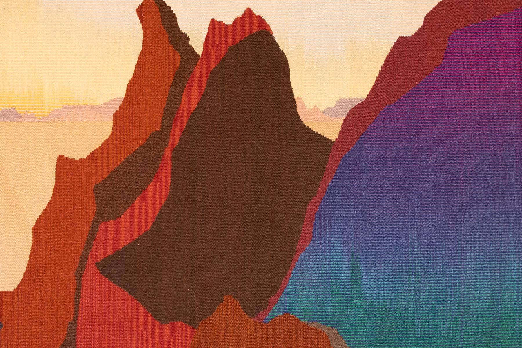 Remarkable over 12’ handwoven tapestry by American artist Janet Taylor depicting red canyon mountain ranges with a distant light yellow sunset along the horizon line. The right quadrant of the composition reflects deeper night approaching with
