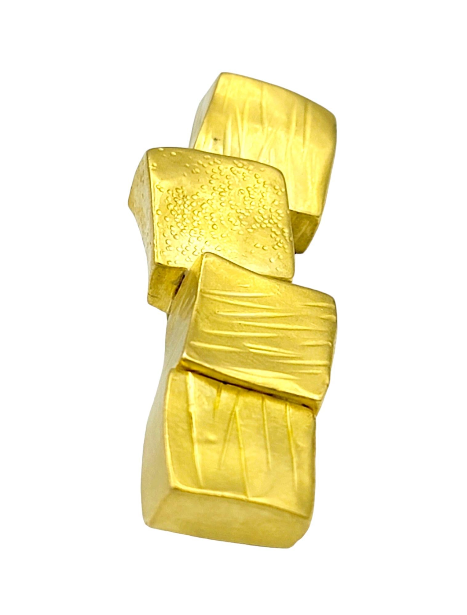 Diese Brosche im geometrischen Stil von Janiye aus strahlendem 22-karätigem Gelbgold ist ein fesselndes Stück tragbarer Kunst. Ihr Design zeichnet sich durch eine Reihe von 4 Goldquadraten aus, die sorgfältig in einer asymmetrischen Linie angeordnet