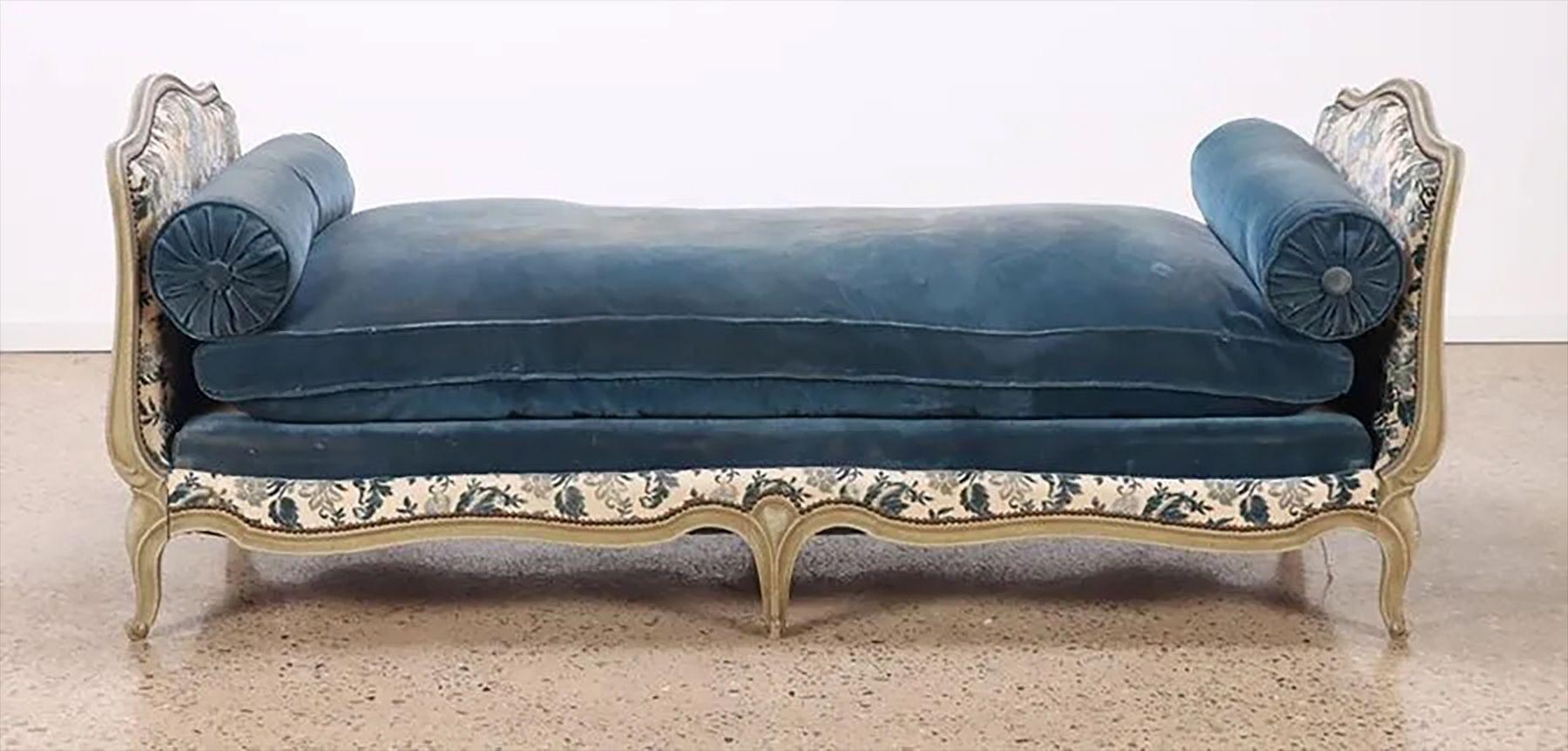 A Carved and Painted Louis XV Style French Daybed in the Maison Jansen Fashion. The Swedish painted finish and carvings having full original fabric with a matching box spring and cushions. This French 1920s daybed or chaise lounge is simply stunning