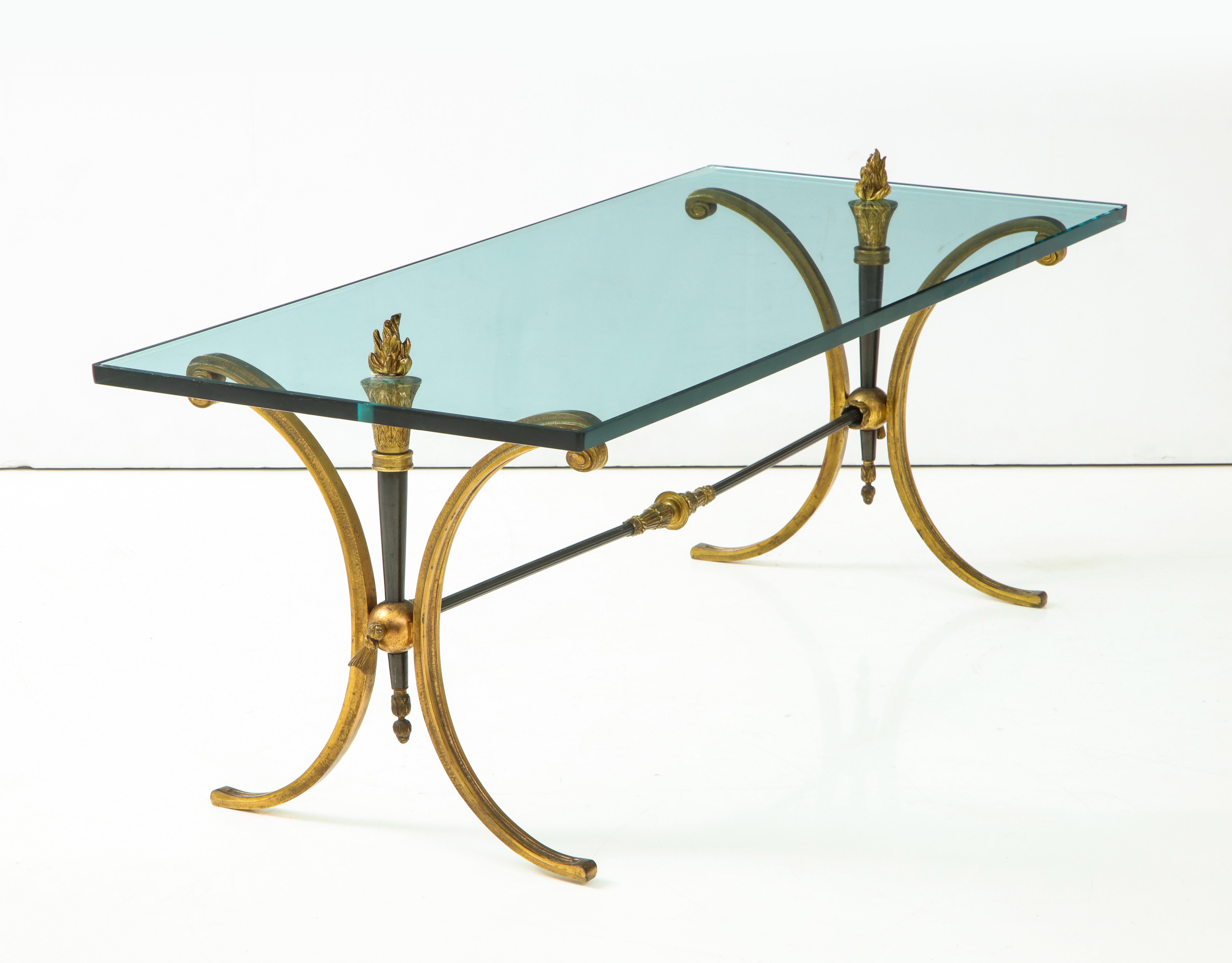 Jansen Empire style bronze coffee table having glass top with flame finial decoration supported on downswept legs and cross stretcher.