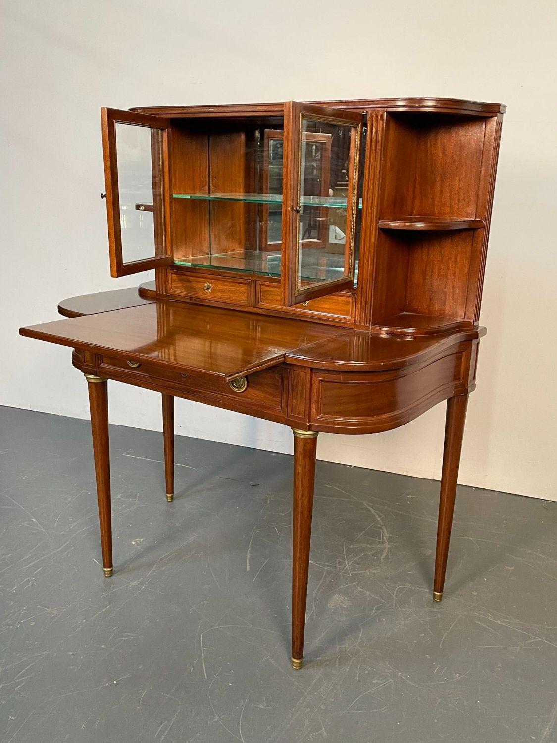 Stamped Jansen Mahogany Desk, Curio Cabinet, Bookcase or Vitrine, Louis XVI 
A finely constructed two-door curio cabinet paneled with bronze beaded banding flanked by two shelf-display, atop a demilune-shaped desk with pull-out writing surface over