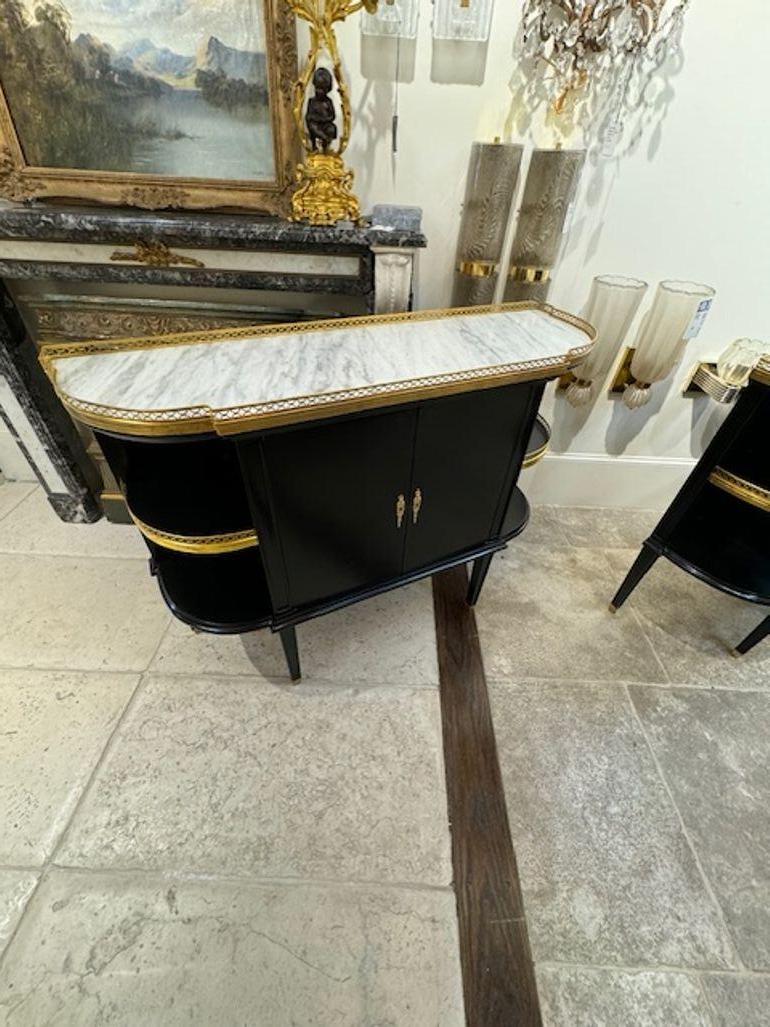 Ravissants serveurs français de style Jansen laqués noir avec détails en laiton et plateaux en marbre de Cararra. Super élégant avec des rangements à l'intérieur et des étagères sur les côtés. Fonctionnel et beau ! Circa 1940 Note : Le prix indiqué