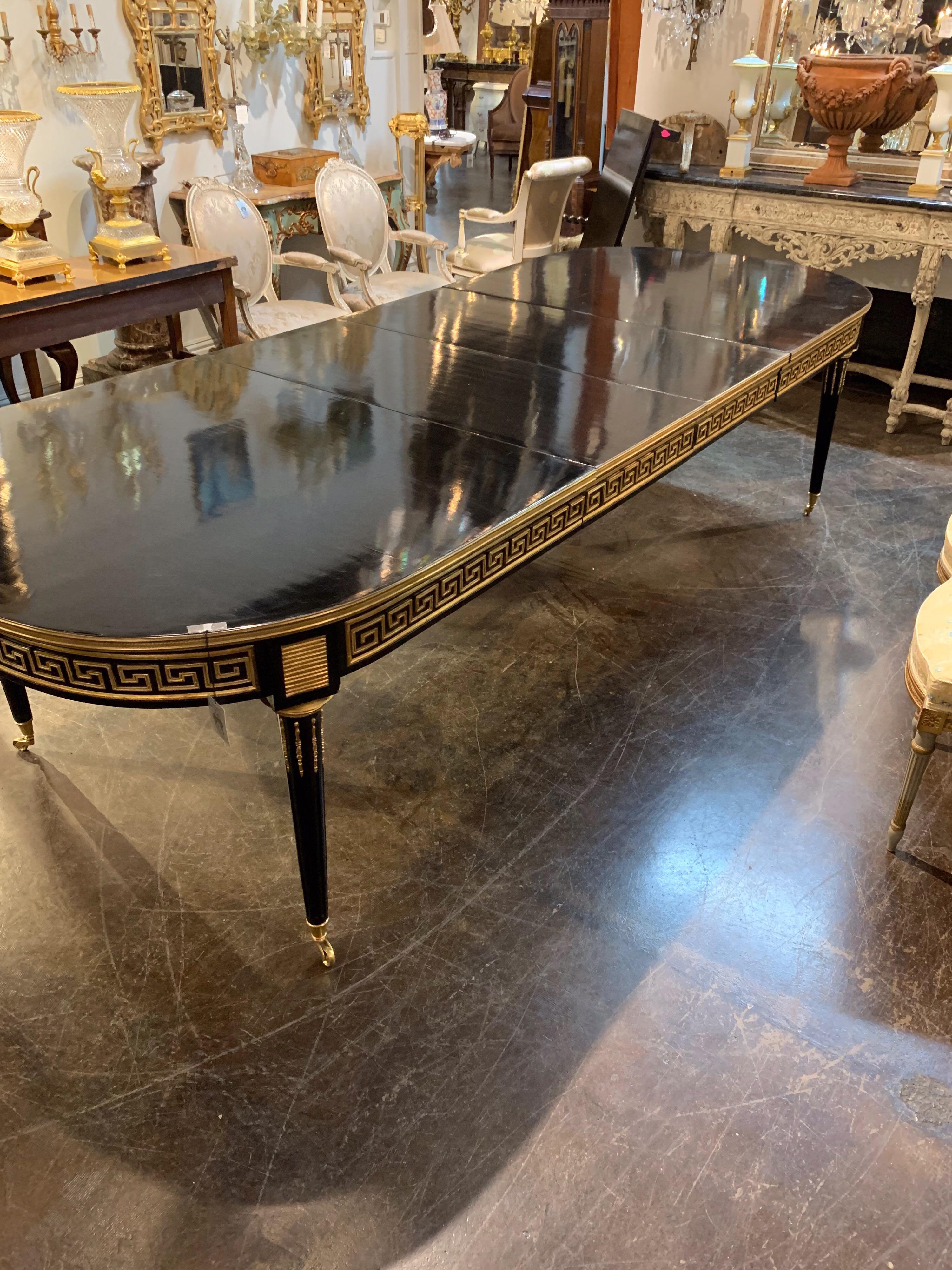Gorgeous Jansen Manner Louis XVI Style black lacquer dining table. The table has an additional leaf and 2 additional legs for support (not shown). Fabulous gilt bronze with Greek Key design around the apron. There are minor blemishes consistent with
