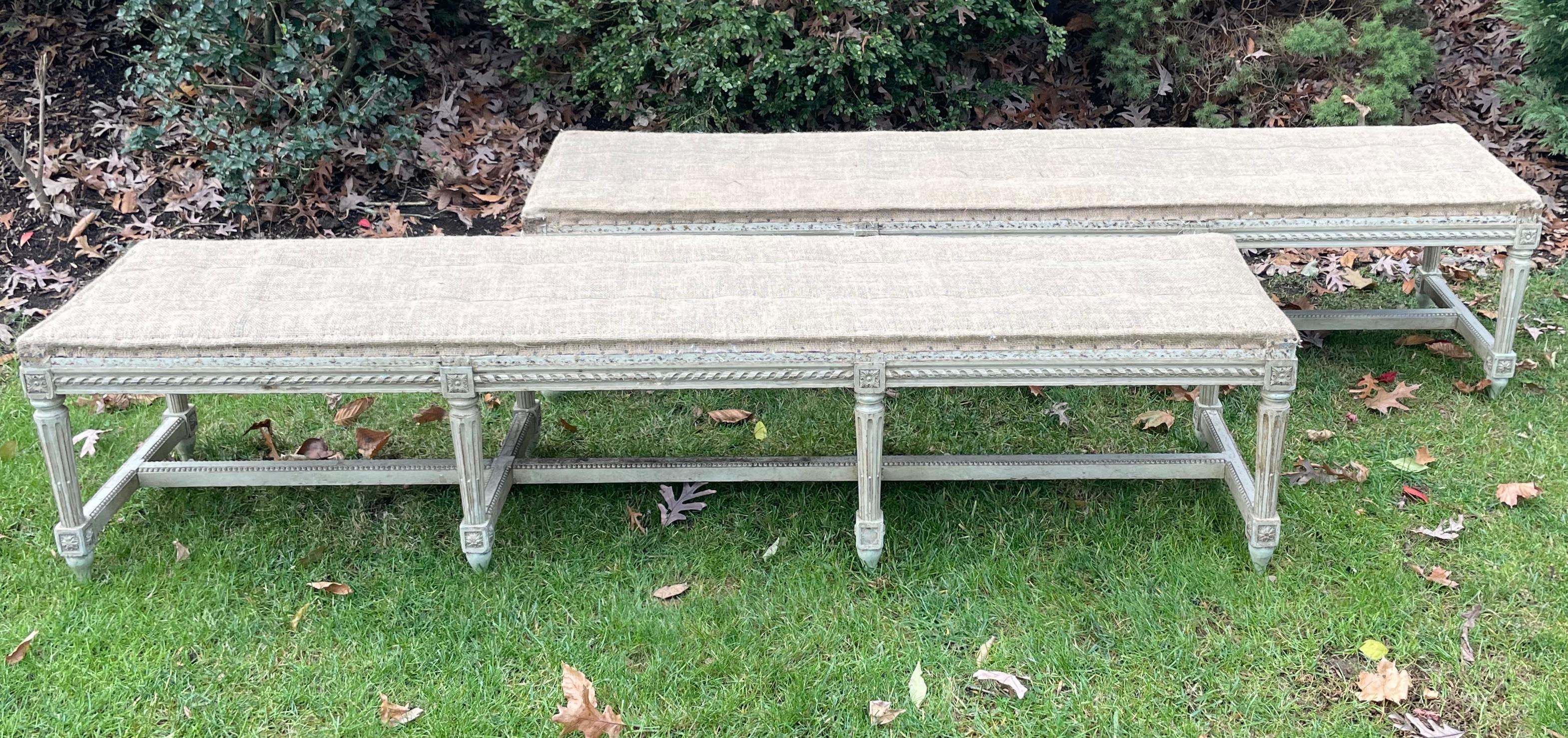 Jansen neoclassical Louis XVI bench. Six foot six inch long neoclassical wood carved bench in original vintage condition with burlap upholstered top on eight wood carved fluted legs joined by stretchers and cross stretchers with corner foliate