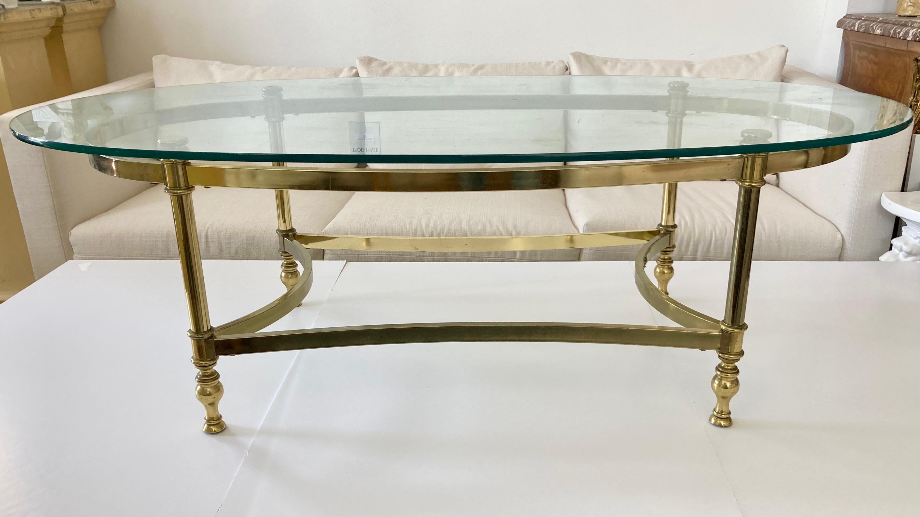 Jansen oval glass top coffee table with brass metal base. Very nice classic French Jansen details. Oval Jansen tables are a nice fit into most seating arrangements. From a fabulous Beverly Hills estate. Some age on the glass and metal base but adds
