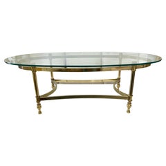 Jansen Table basse ovale avec plateau en verre et cadre métallique en laiton