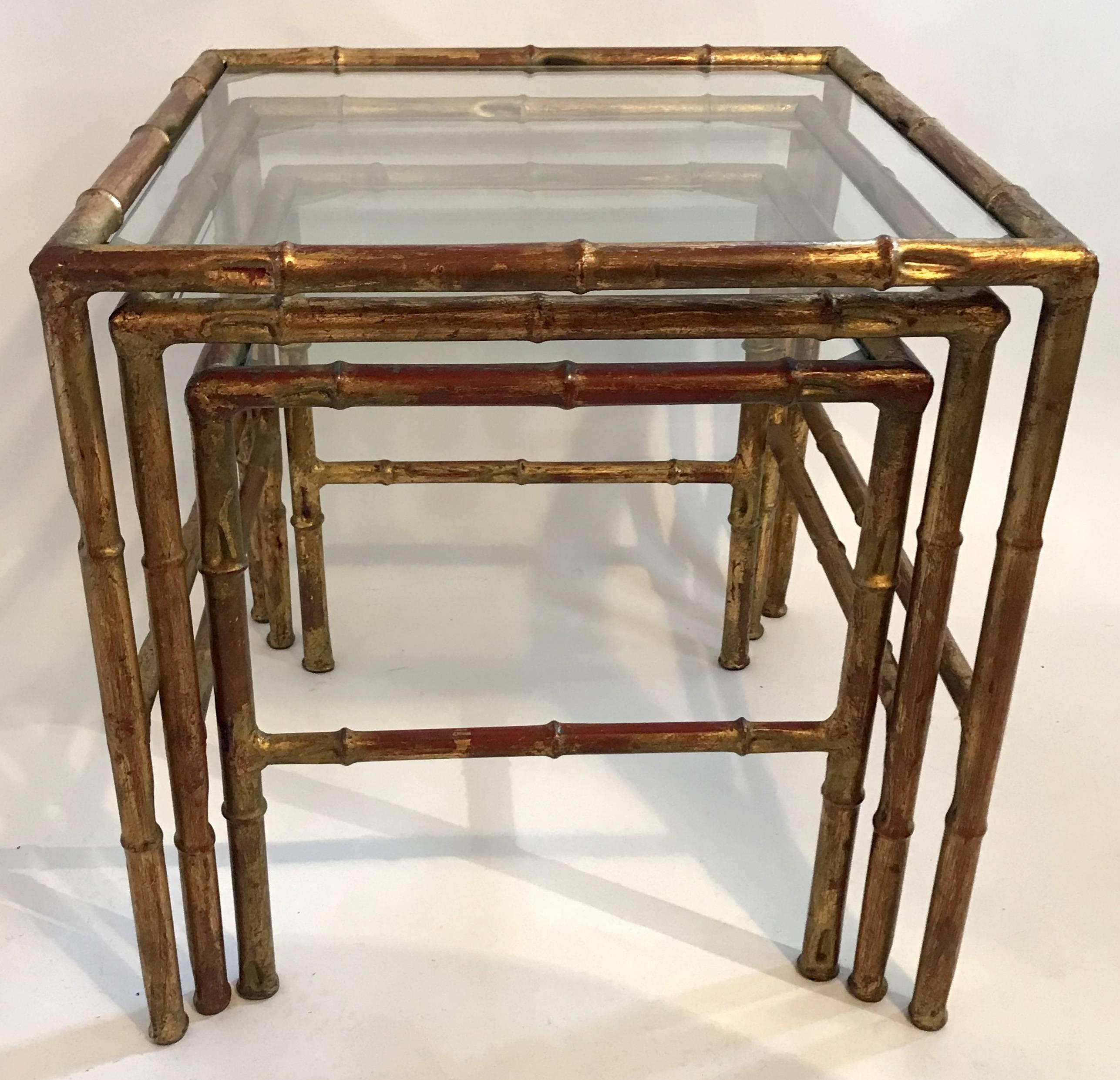 A wonderful Mid-Century Modern set of three faux bamboo, gilt gold metal nesting / stacking tables in the manner of Baguès & Jansen with clear glass tabletops, circa 1950s.

Sold and priced as a set. 
Approximate sizes of each table:
17 1/2