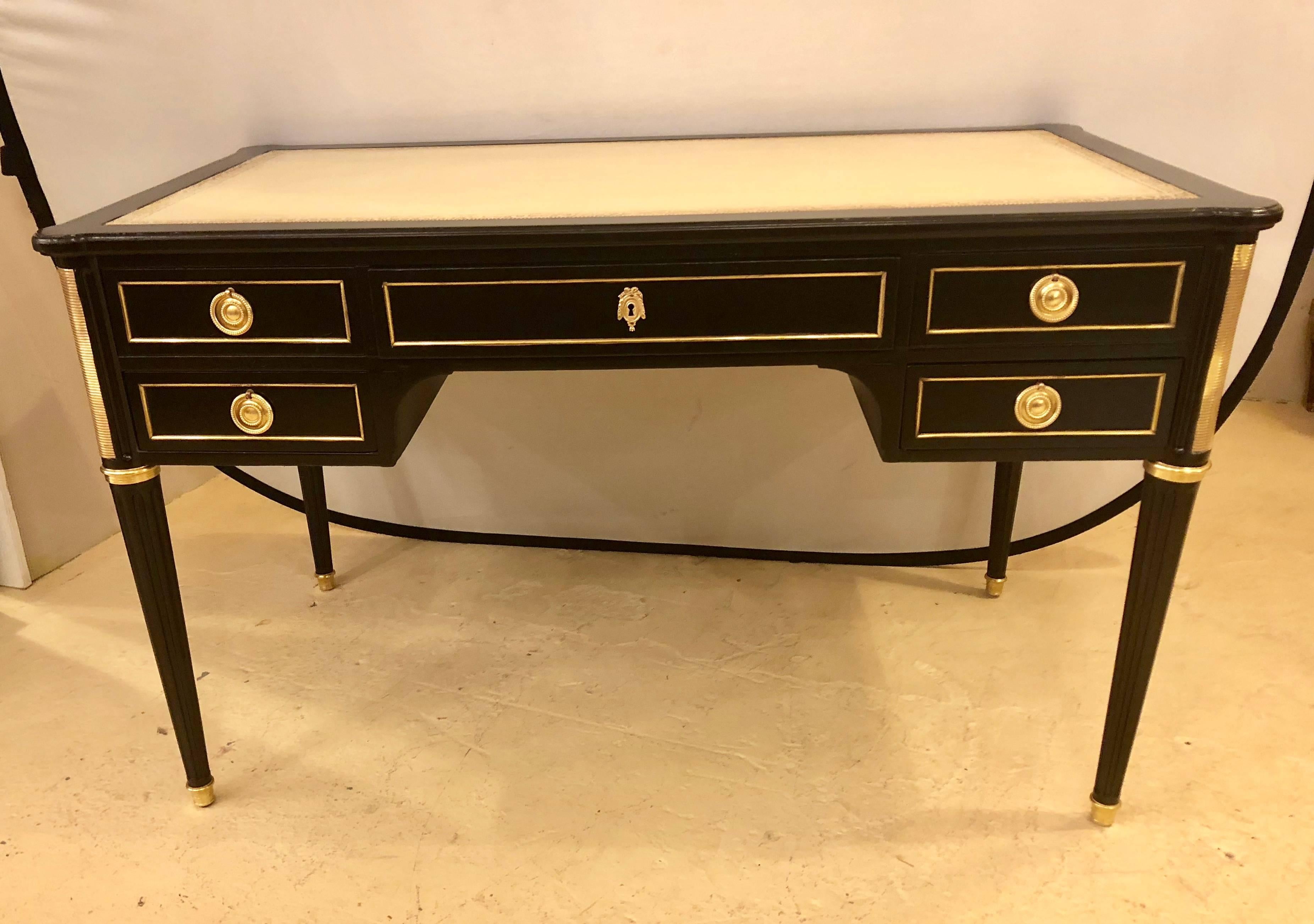 A Jansen style Hollywood Regency bronze-mounted ebony desk in Louis XVI fashion. Having all the earmarks of the Maison Jansen flair this fine bronze-mounted desk sits on bronze casters with reeded and tapering legs terminating in bronze capitals