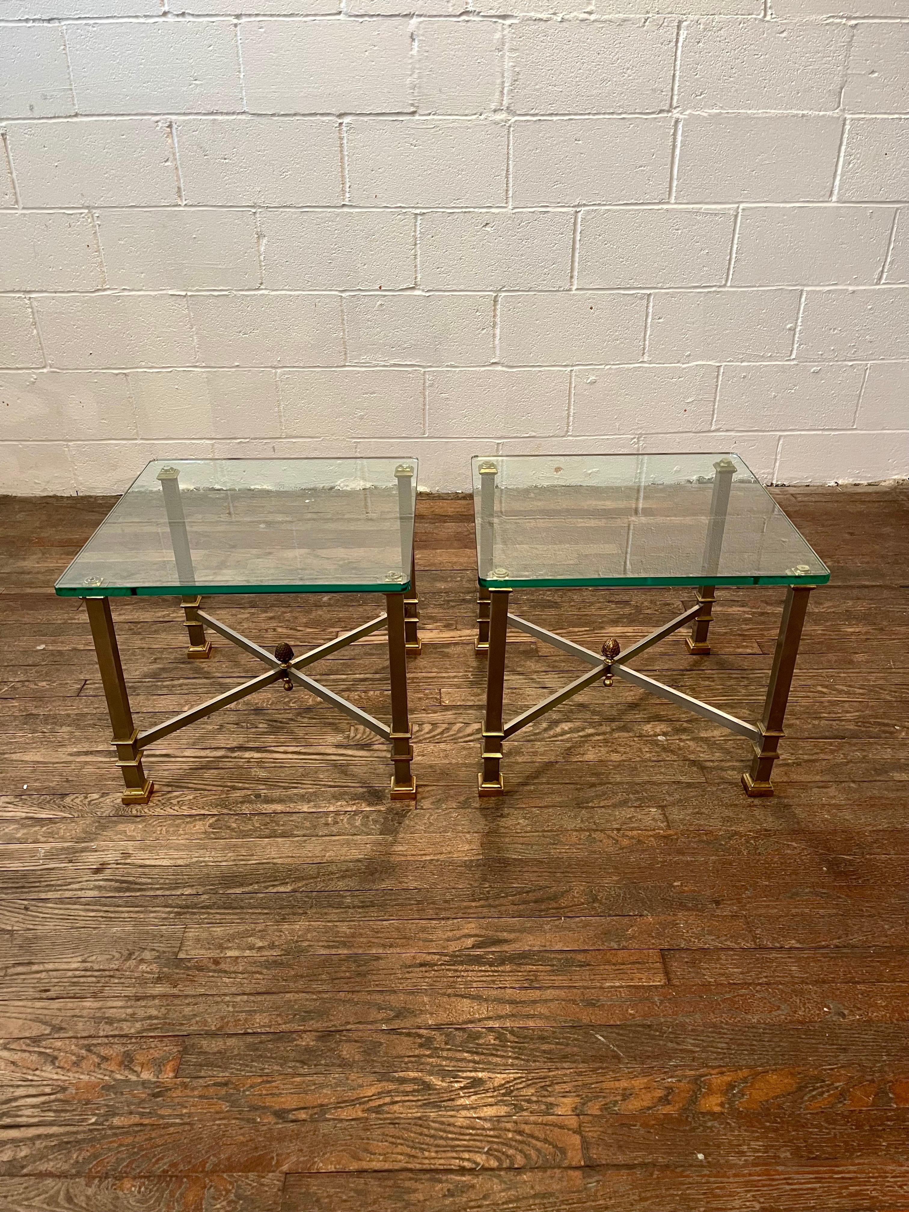 Stunning pair of end tables in the manner of Maison Jansen. Unique square steel leg design with brass accents. Signature brass acorn finial tie it all together. Thick 1/2