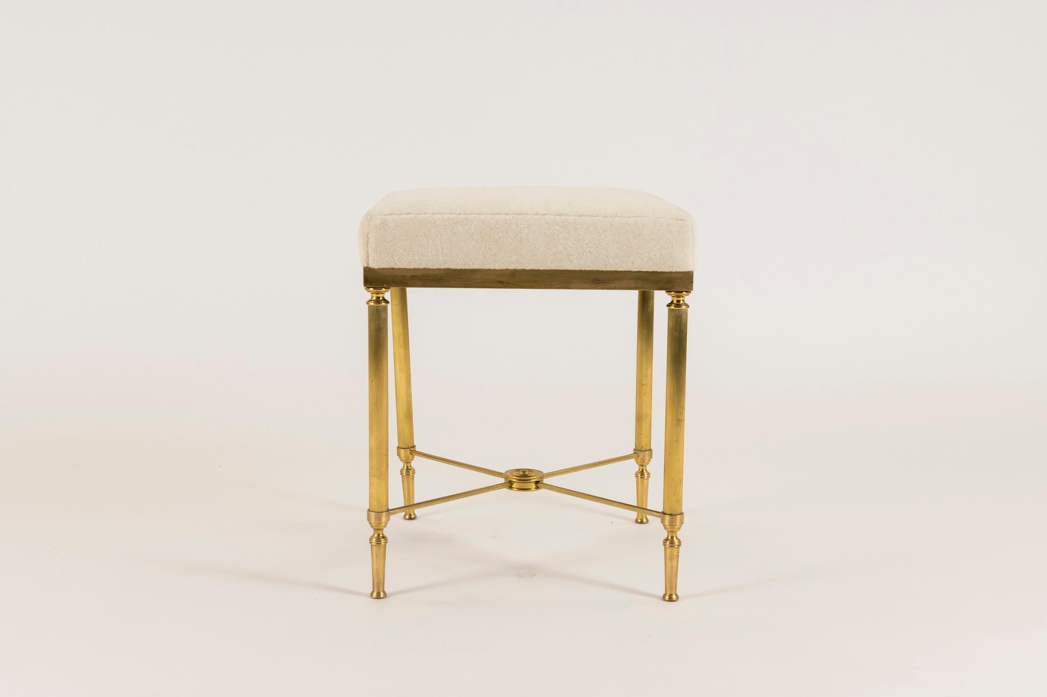 A beautifully constructed vintage neoclassical style detailed brass bench with tapered and fluted legs and radiused stretchers in the style of Maison Jansen. Seat is upholstered in a creamy Pollack Luxe Alapaca Fleece. Also available