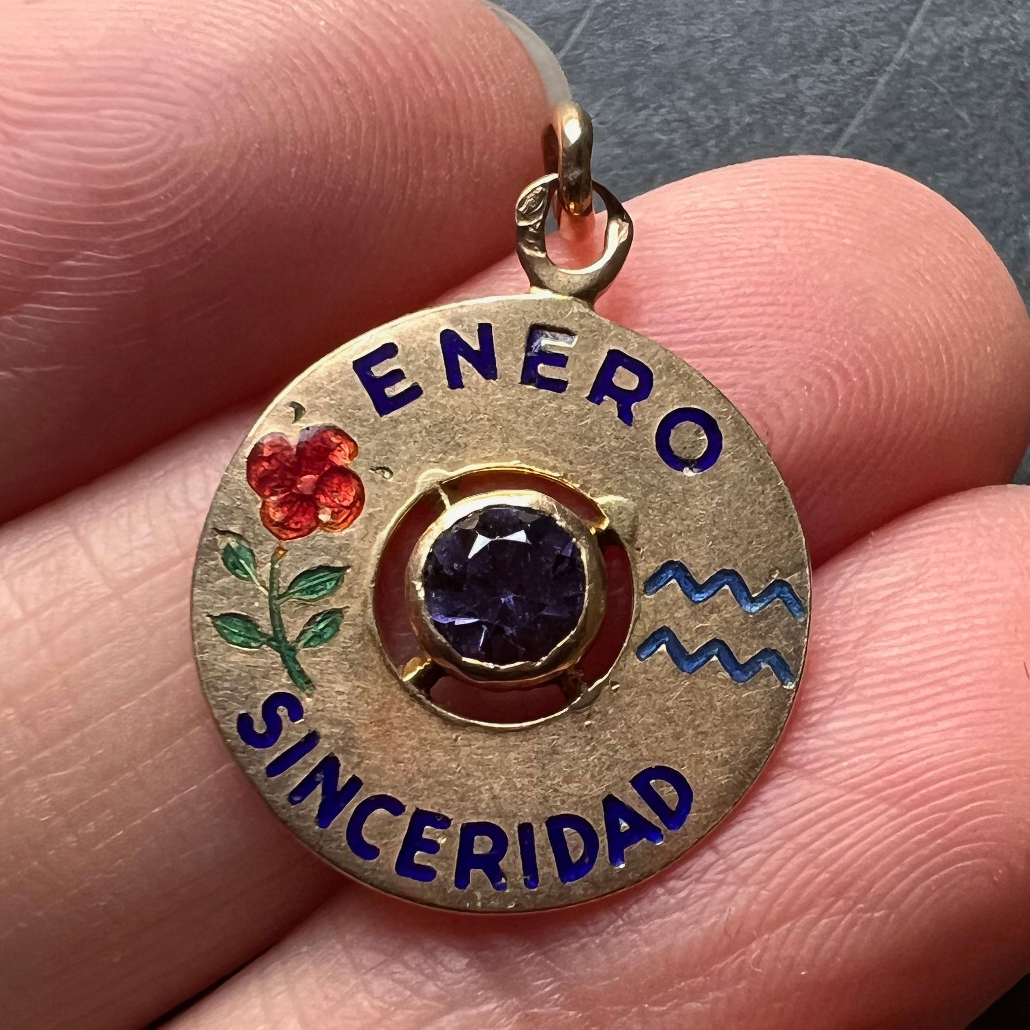 An 18 karat yellow gold charm pendant designed as a gold disc with enamel inlay of 'ENERO SINCERIDAD' (January Sincerity) with the zodiac symbol for Aquarius and a carnation (symbolising devotion, loyalty and love) in enamel, and set to the centre