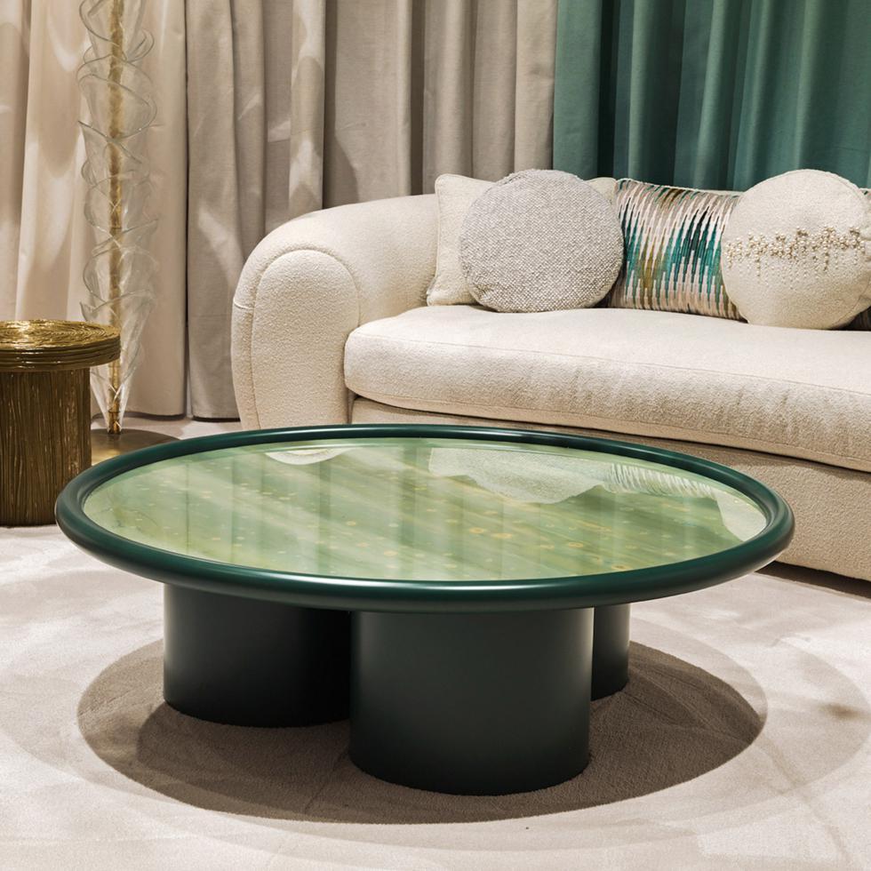 Wooden round coffee table with three feet with cylindrical base. Glass top with hand-painted decoration in different colors with gold details. The edge of the top and feet are glossy and lacquered in green color.