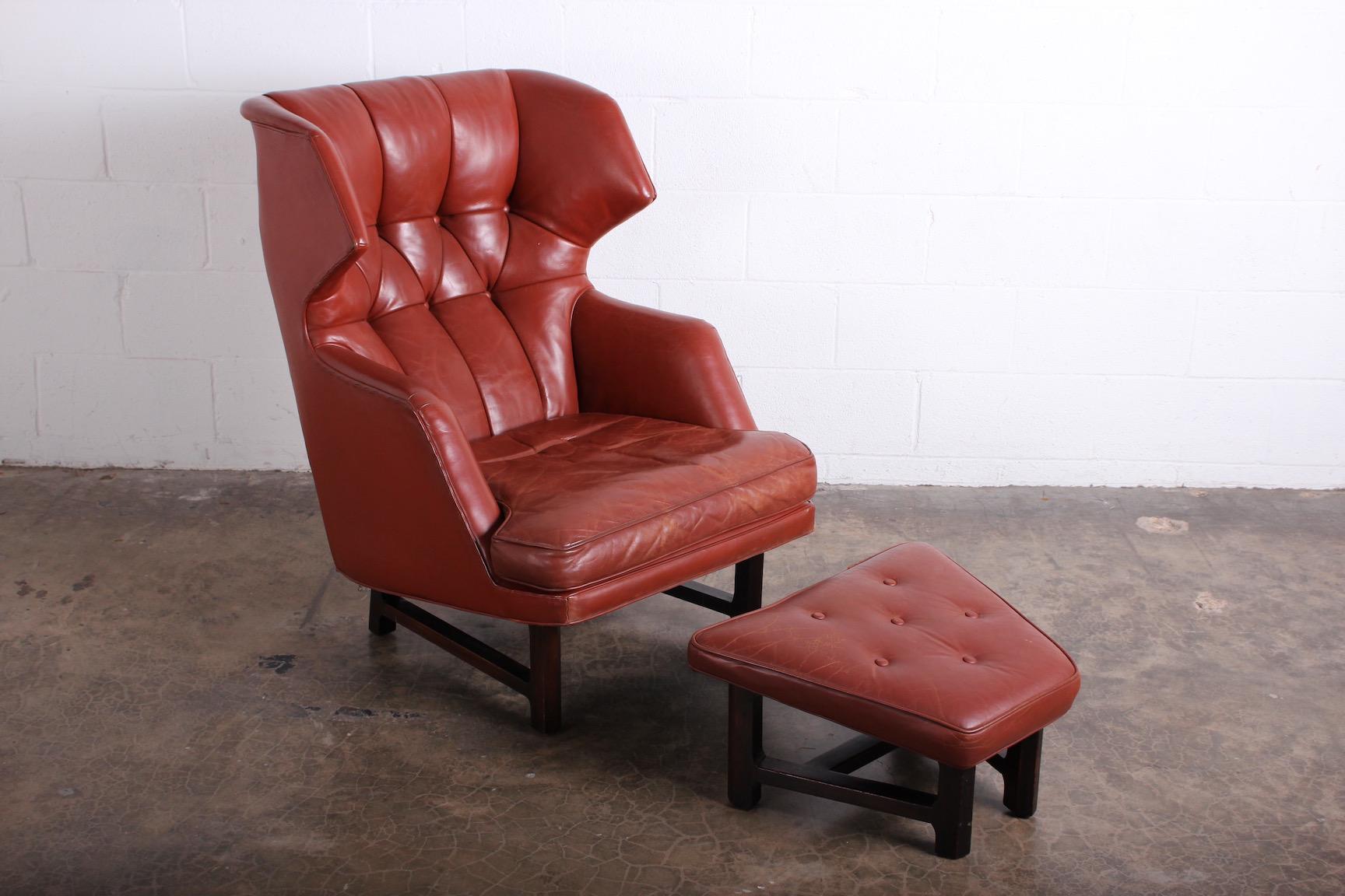 A Janus wing chair and ottoman with mahogany base and original leather. Designed by Edward Wormley for Dunbar.