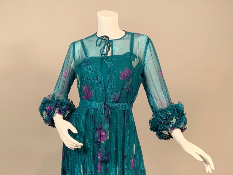 Jany de Saint Orens has designed a beautiful teal and purple printed silk chiffon evening dress. It has a demure tie at the neckline above an opening to the waistline at the center front revealing the matching silk slip underneath. The sleeves have
