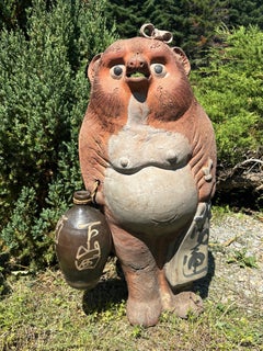 Escultura japonesa antigua de gran tamaño de un tanuki, un personaje popular femenino sonriente