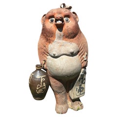 Escultura japonesa antigua de gran tamaño de un tanuki, un personaje popular femenino sonriente