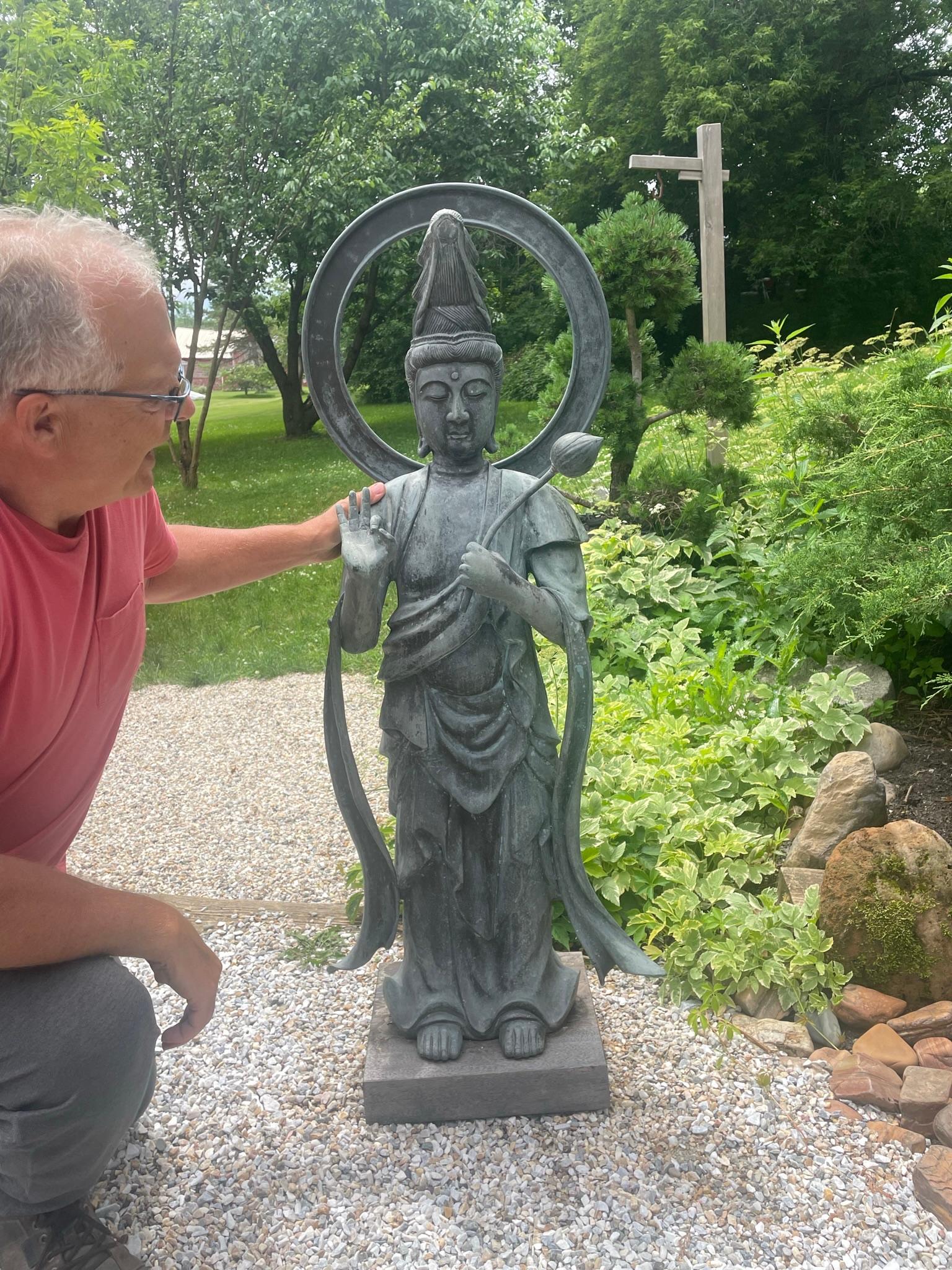 Un bon choix pour le jardin ou une exposition spéciale dans une galerie d'intérieur

Japon, un élégant Kanon Maitreya ou Guan Yin debout, finement moulé en bronze antique, serrant une branche de lotus - un signe de pureté - et avec une belle