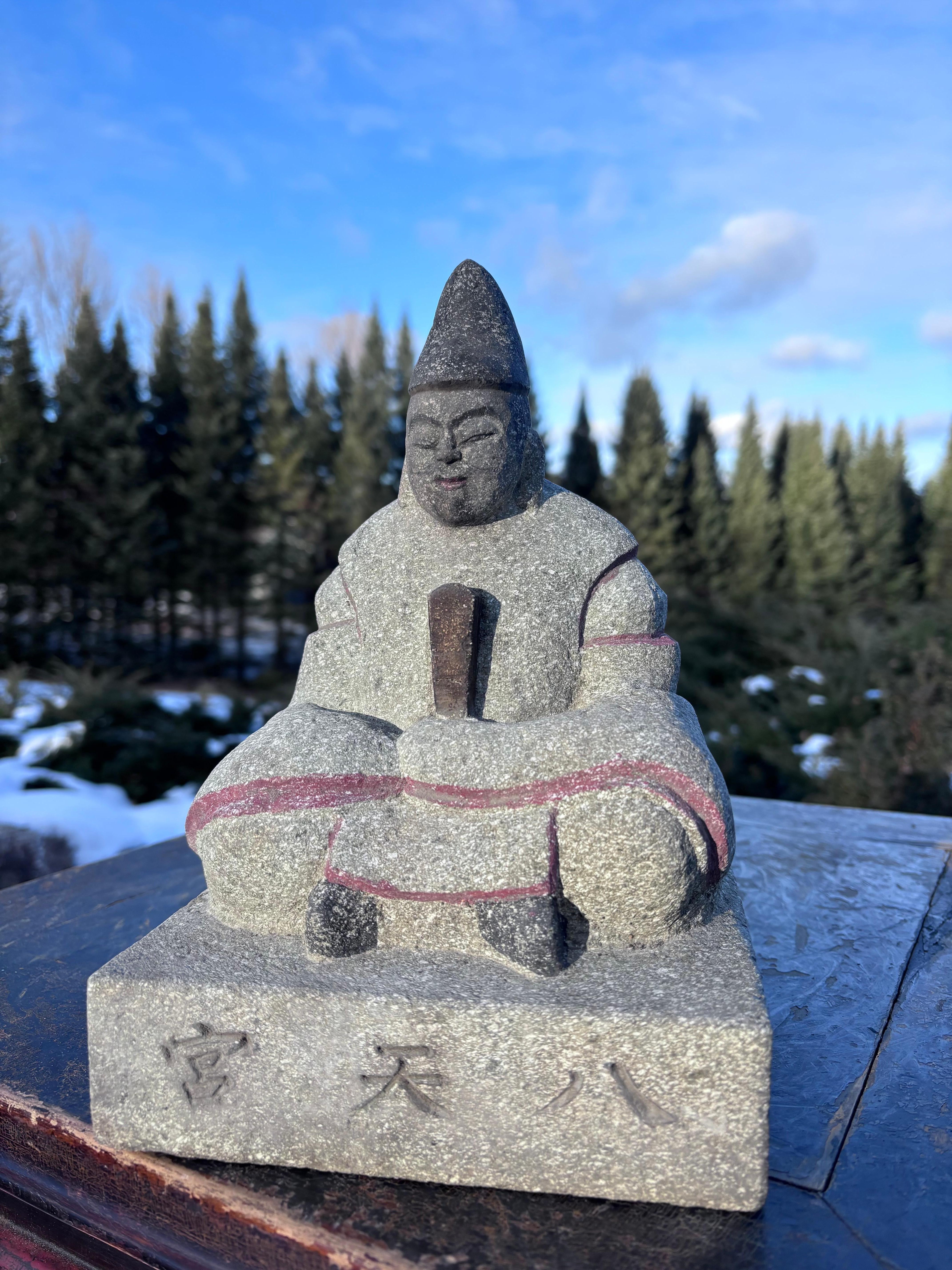 Japan, an older 20th century hand-carved and hand painted stone image of a scholar

Signed base: Hachi Ten Gu (name of shrine)

He sits upon a square base wearing his notable hat and clutching a book.

This image was hand-carved in a traditional