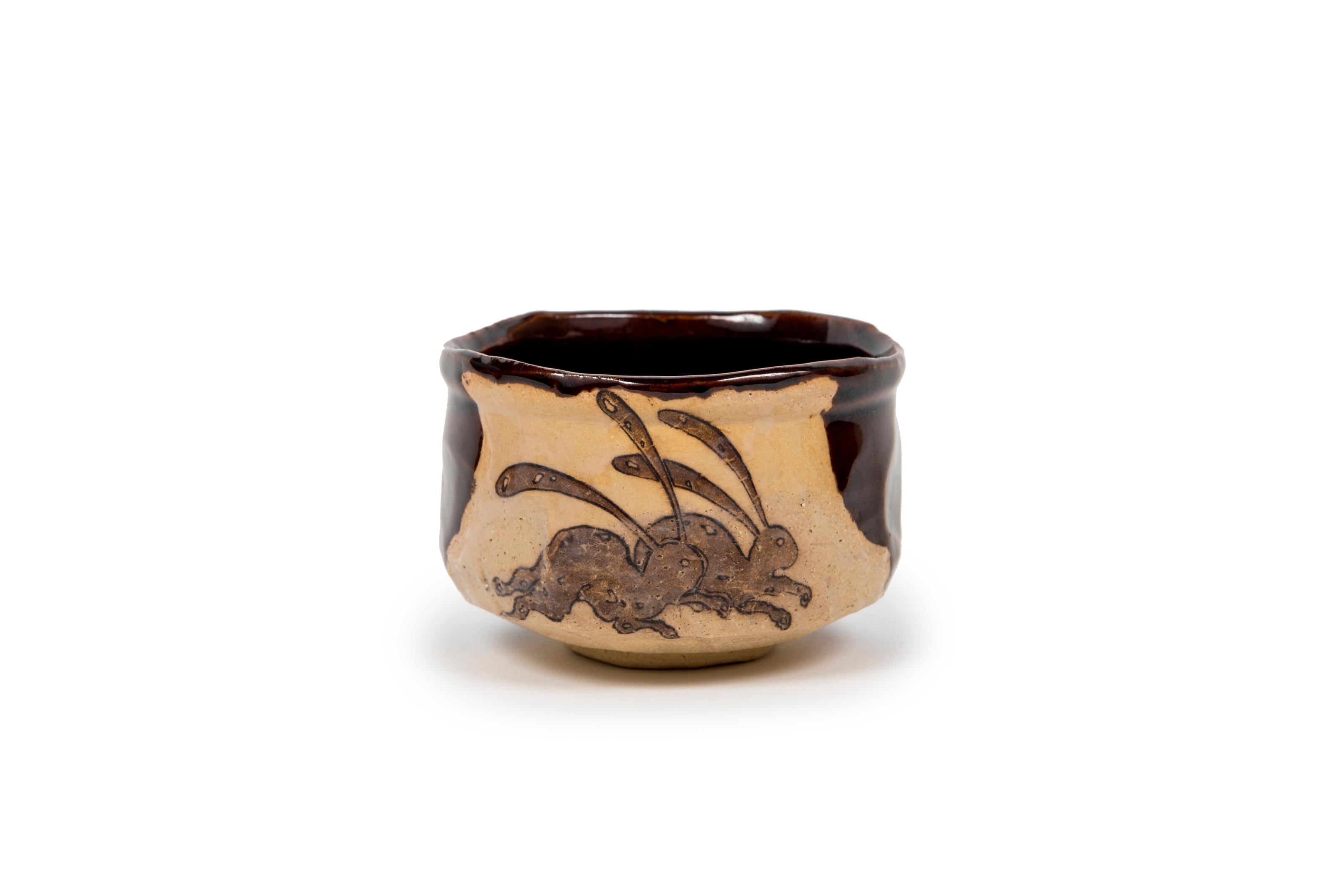 Matcha bowl in clay decorated with two hare, partly glazed.

A fine contrast between the unglazed foot, which retains the raw color and rough, matt appearance of the clay, and the rest of the bowl, which is partly glazed with a brown layer with a