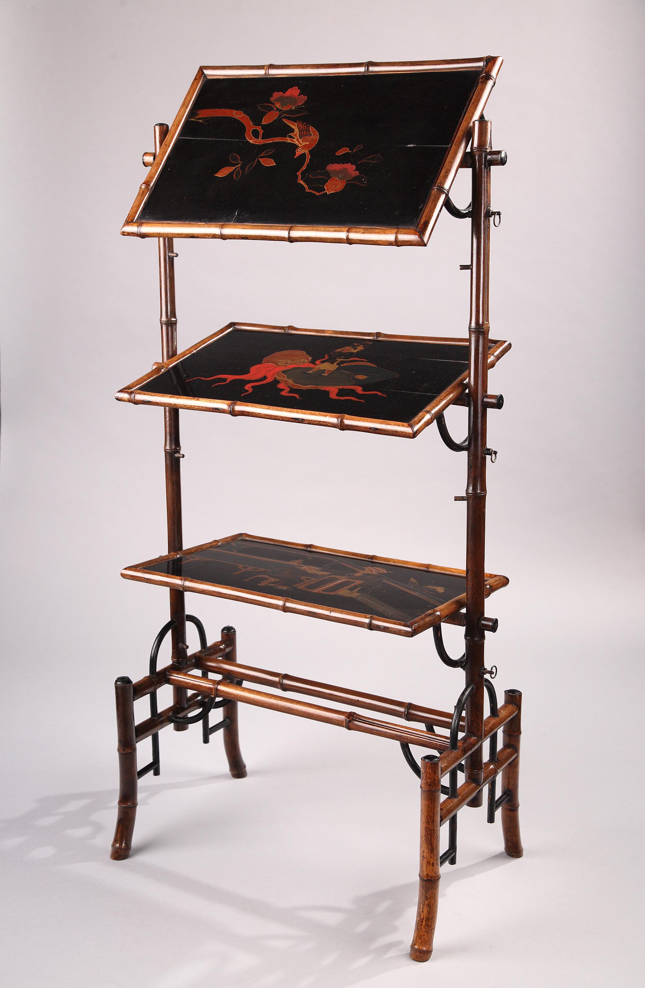 Charming Japanese style servant table executed in varnished bamboo and Japan lacquer. Made up of three rectangular rocking trays, tastefully decorated with gold-and-red motifs on a black background, depicting a bird on a branch, an octopus with a