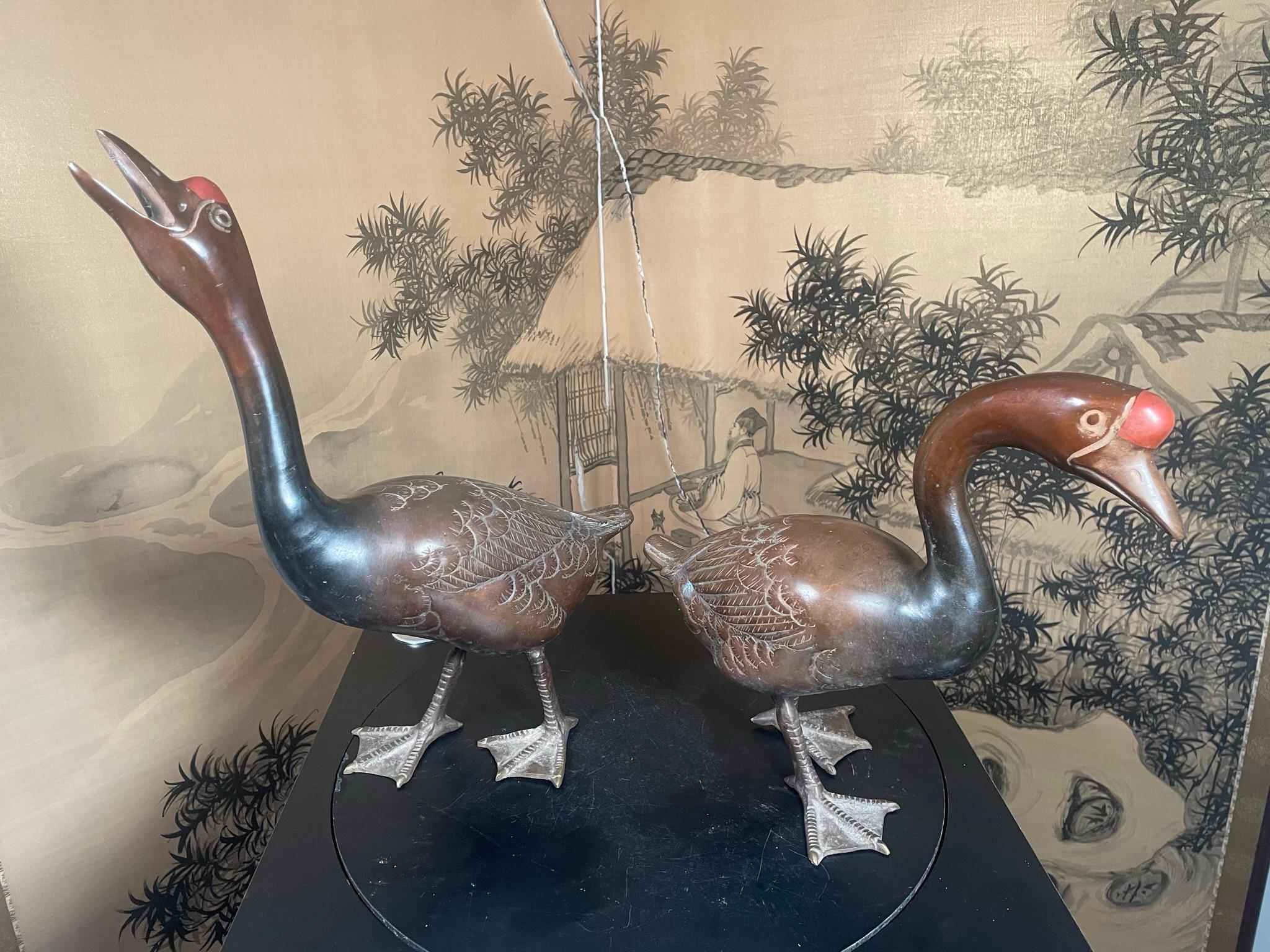 A fine pair (2) of large scale Japanese hand-cast bronze geese or ducks with red knob heads, mahoghany colored surfaces, and highly detailed plumage, heads, tails, webbed feet, and wings. They are signed on the bottoms of their feet.

Attractive