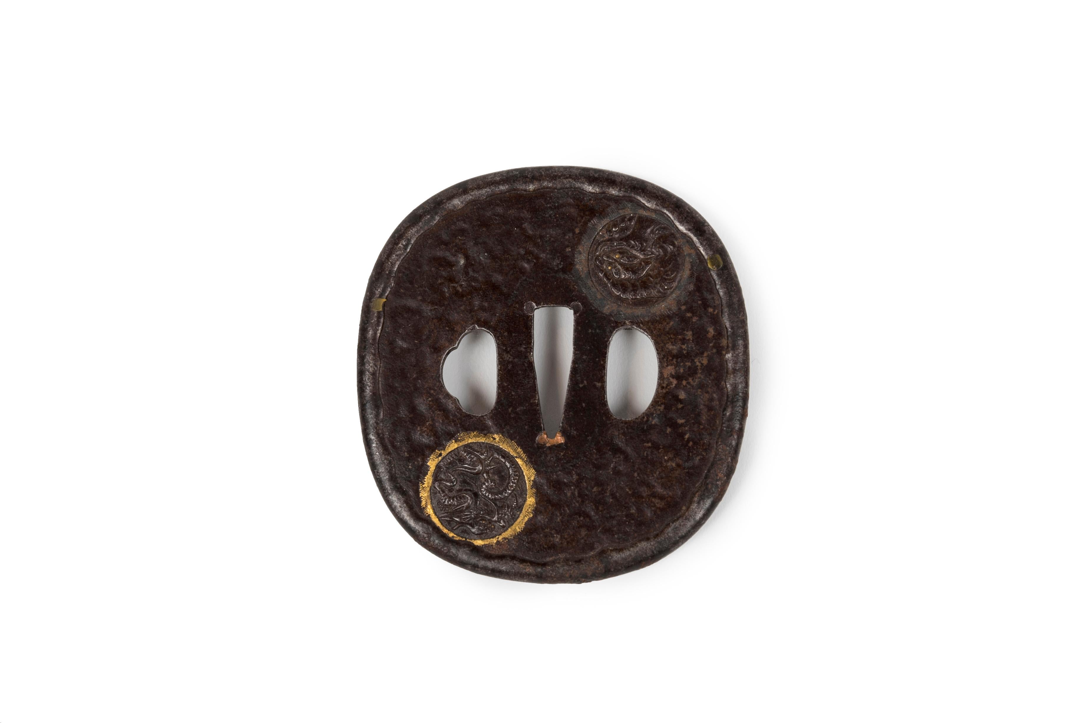 Ovoid-shaped (nagamarugata) iron tsuba hammered and chased with medallions. On one side, medallions of a dragon with gold highlights and a komainu (or shishi – lion dog guarding the temple). On the other one, a medallion of waves and clouds with