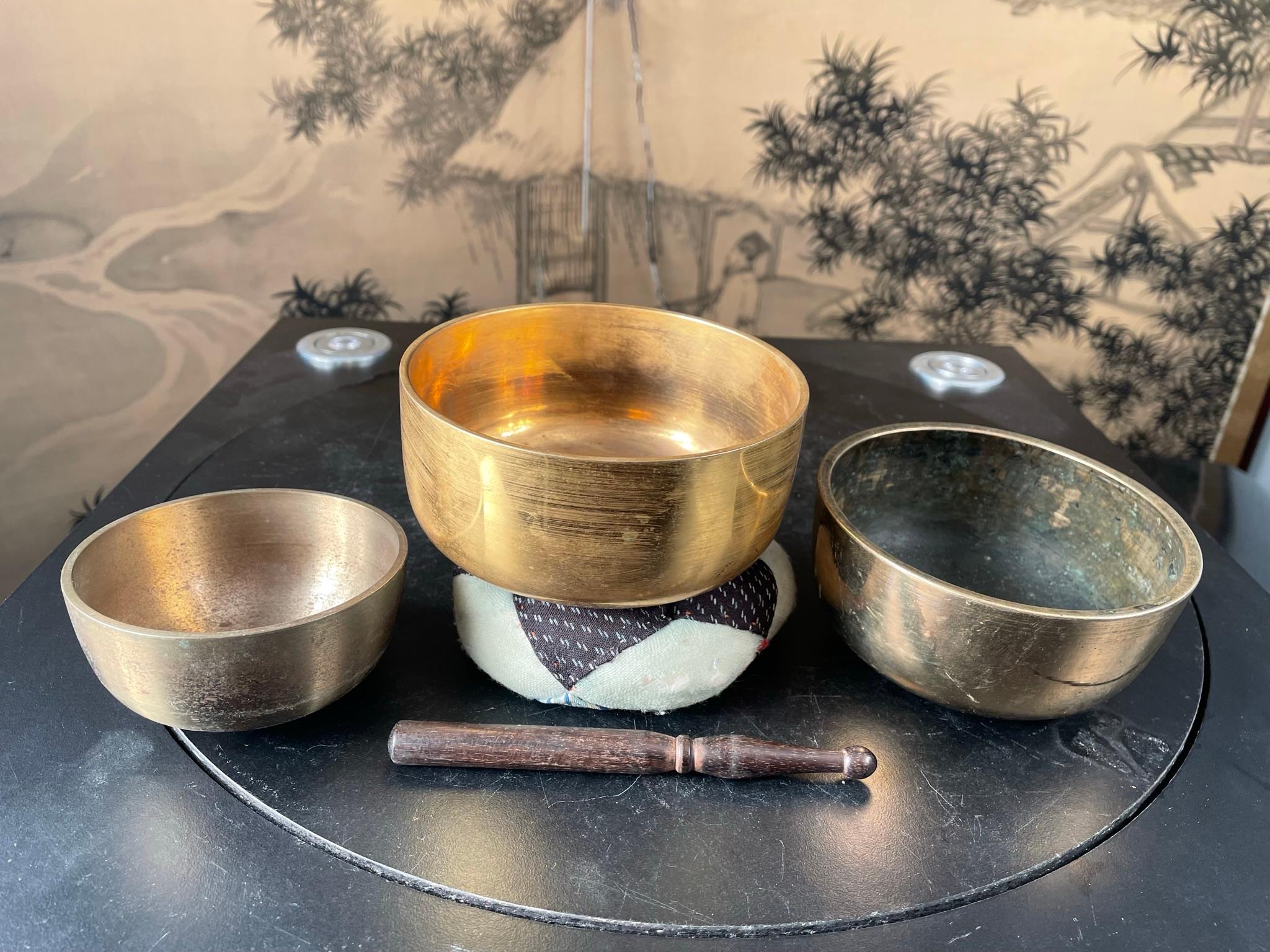 From Japan, a very nice collection of three (3) small to medium scale mid-20th century bronze temple meditation bells with handmade cushion and hardwood striker set.

Serene resonating sound guaranteed to please you.

Dimensions: Largest bell 4