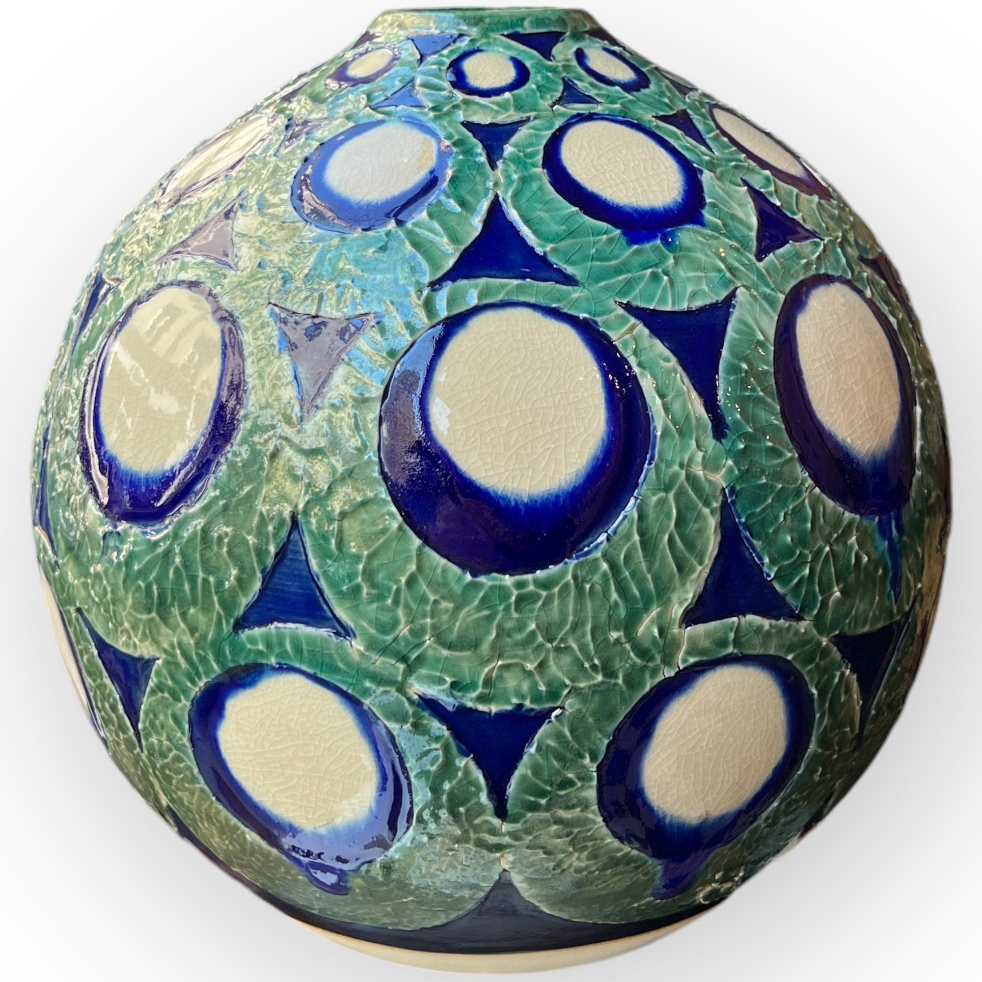 Vase by Kanzan Shinkai,born in 1912
This vase is a fine example of Kanzan Shinkai's work. It features an intricate design, with raised circular patterns, using contrasting colors such as blue and green, typical of Shinkai's style. The circles,
