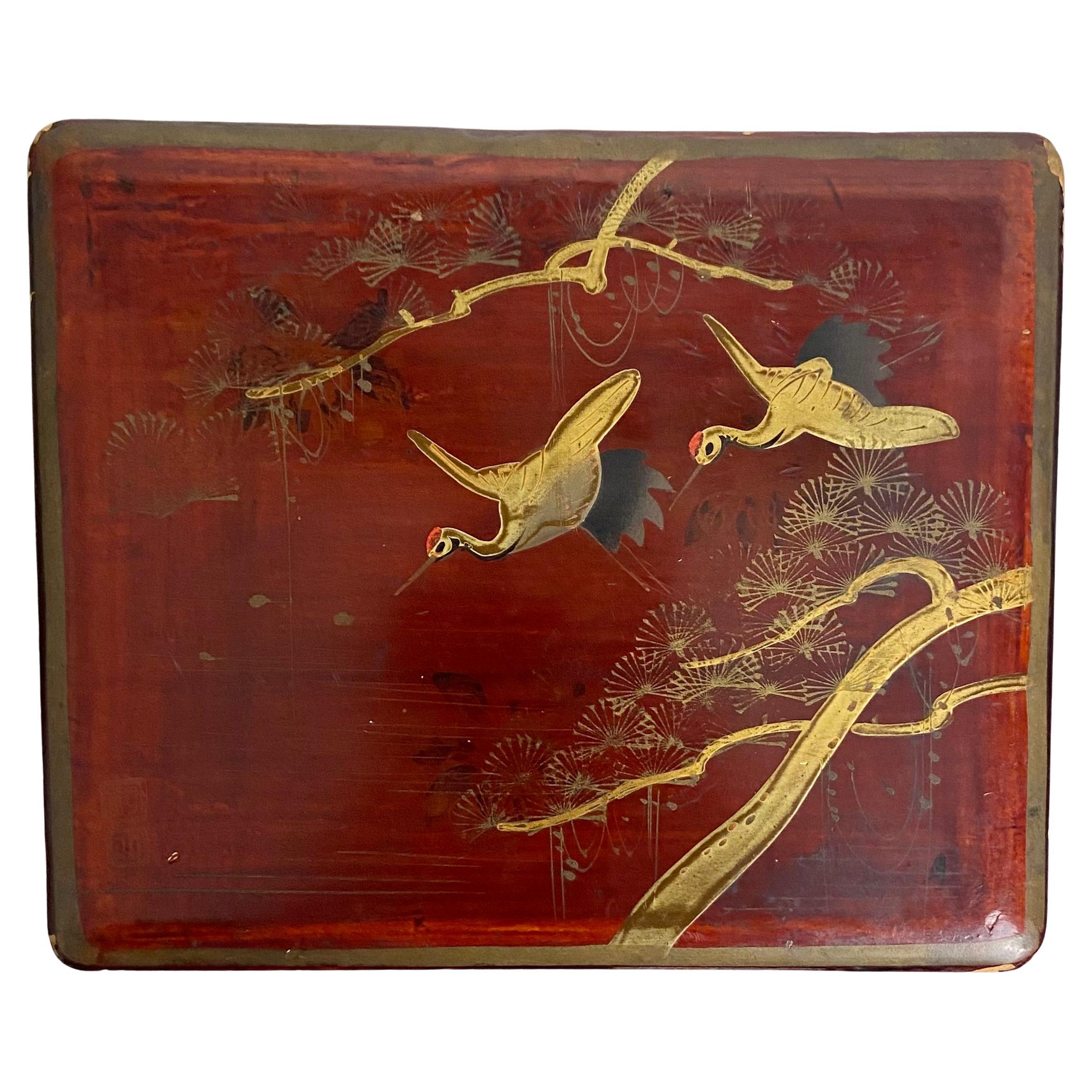 Schöne japanische Kiste aus rot lackiertem Holz.
Der Deckel ist mit goldenen Reihern und blühenden Zweigen verziert und vom Künstler signiert. Um die Schachtel herum sind schwarze Blumen gemalt.
Die Innenseite der Schachtel ist mit einer schwarzen