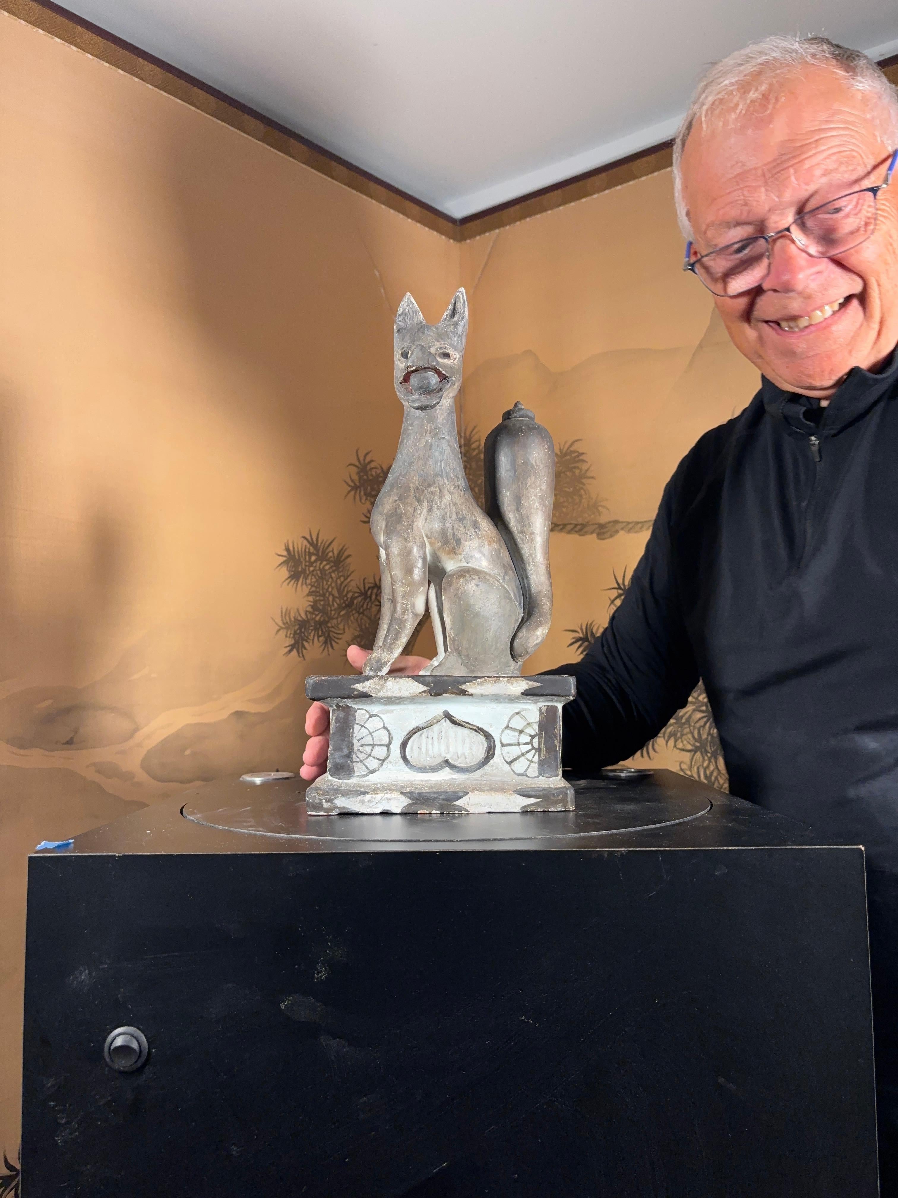 Antico santuario shintoista giapponese in ceramica della volpe Inari e del Kami (dio) shintoista. 

I rari occhi di vetro e i resti di vernice rossa (bocca) e bianca sulla base sono ancora presenti e tiene in bocca il sacro hoju.

Dimensioni: 16