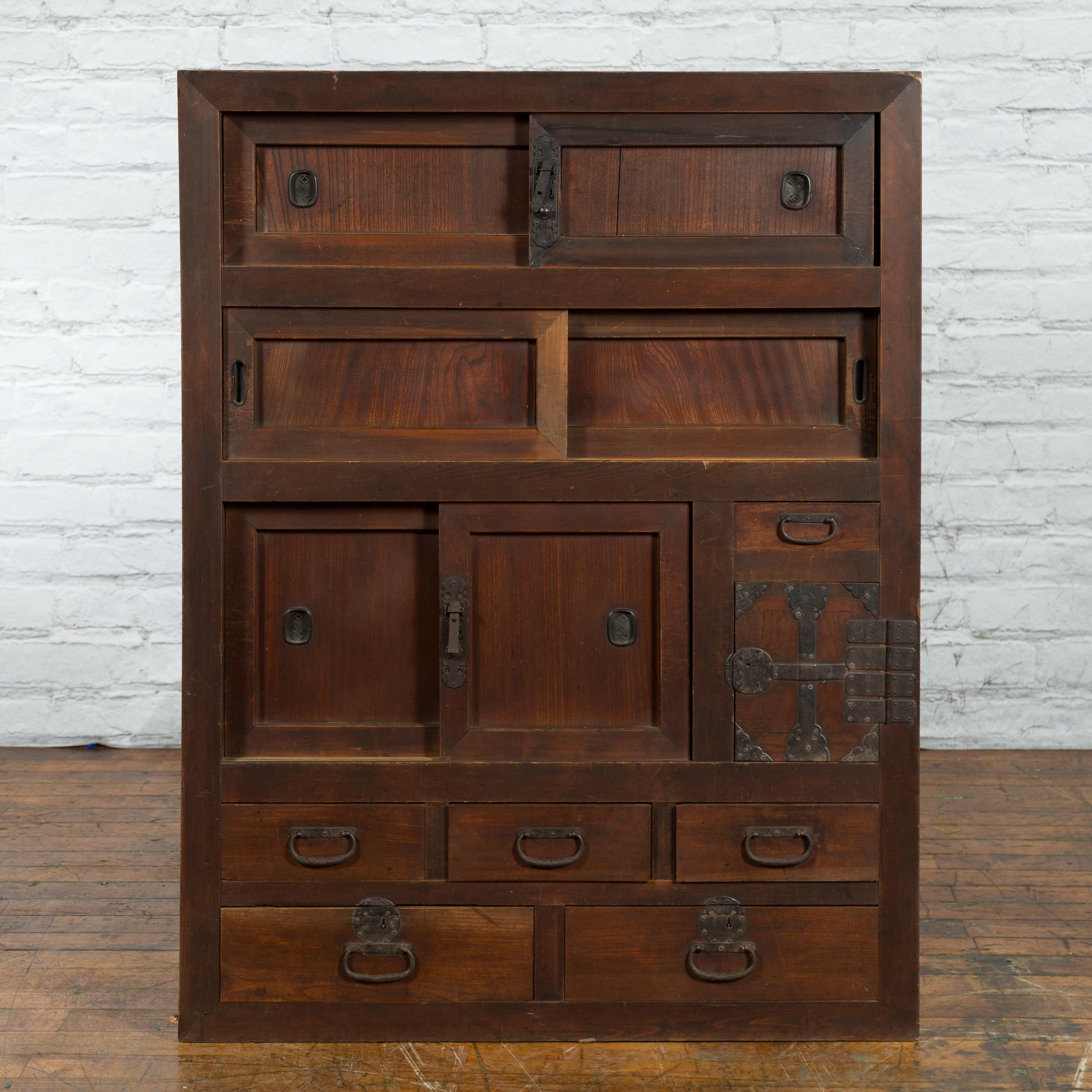 An antique Japanese kitchen cabinet from the 19th century, with sliding doors, drawers and iron hardware. Created during the 19th century, this kitchen cabinet is a fine example of Japan's mastery of cabinetry. The piece showcases a linear