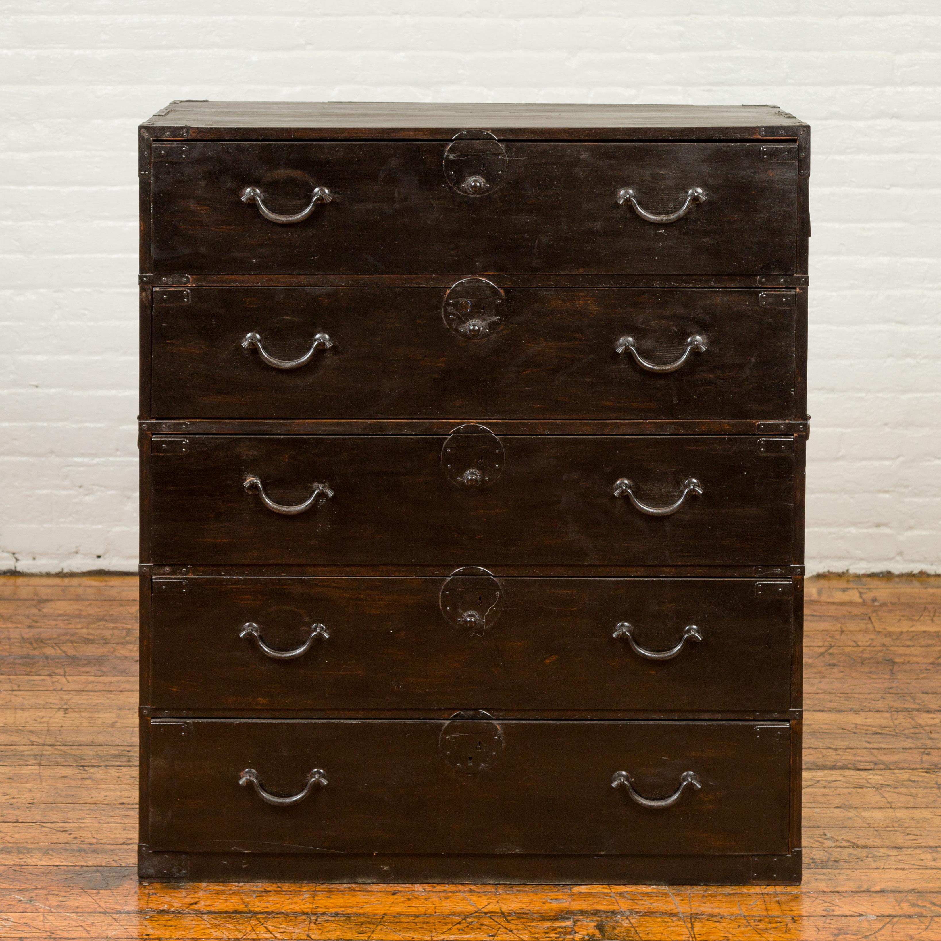 A tall Japanese Meiji period tansu clothing chest from the 19th century, with five drawers, dark patina and iron hardware. Born in Japan during the Meiji period, this single section tansu traveling chest features a rectangular top sitting above five