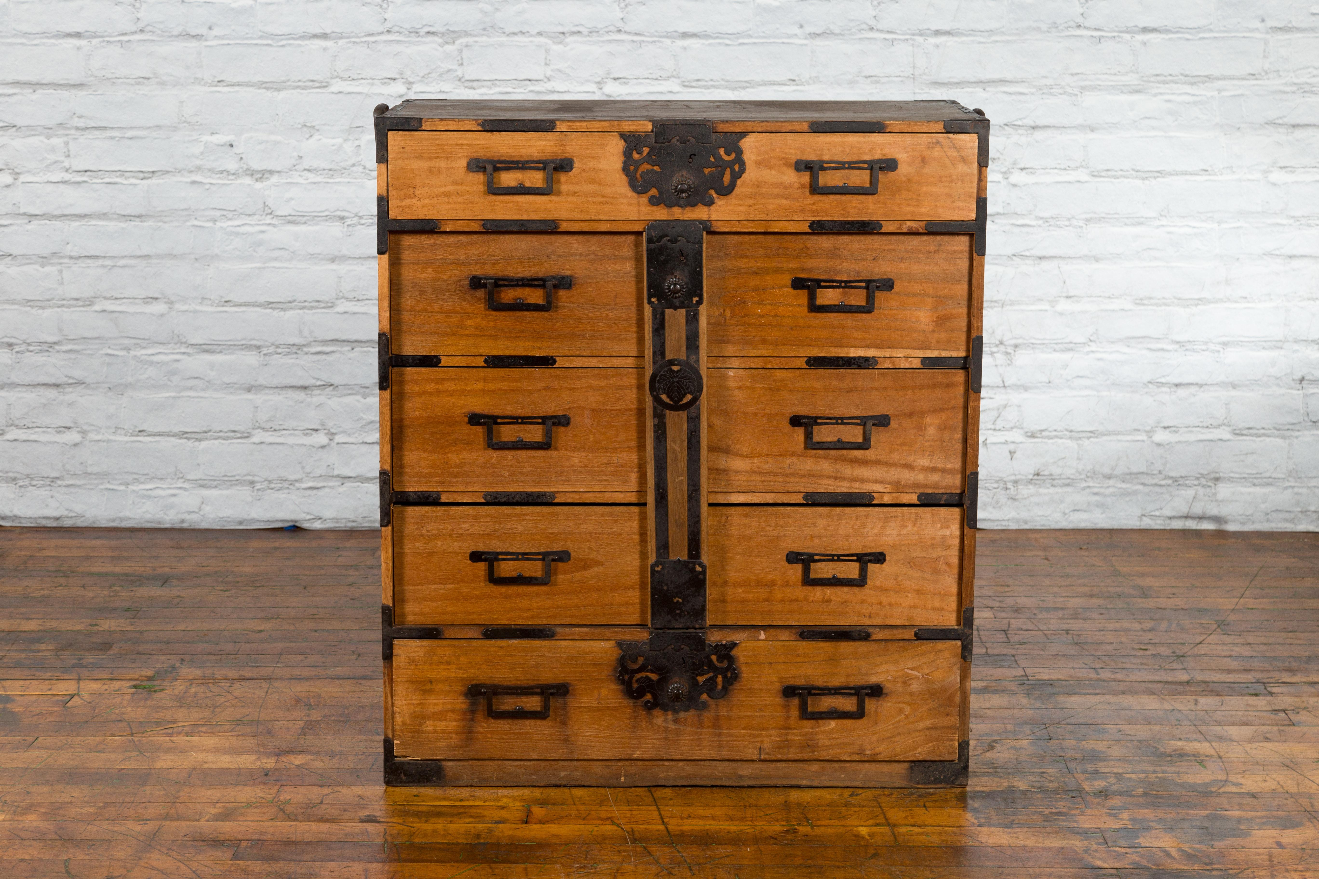A Japanese Meiji period tansu traveling chest from the 19th century with multiple drawers, and iron hardware. Created in Japan during the Meiji period, this tansu chest captures our attention with its natural wood grain and perfectly organized