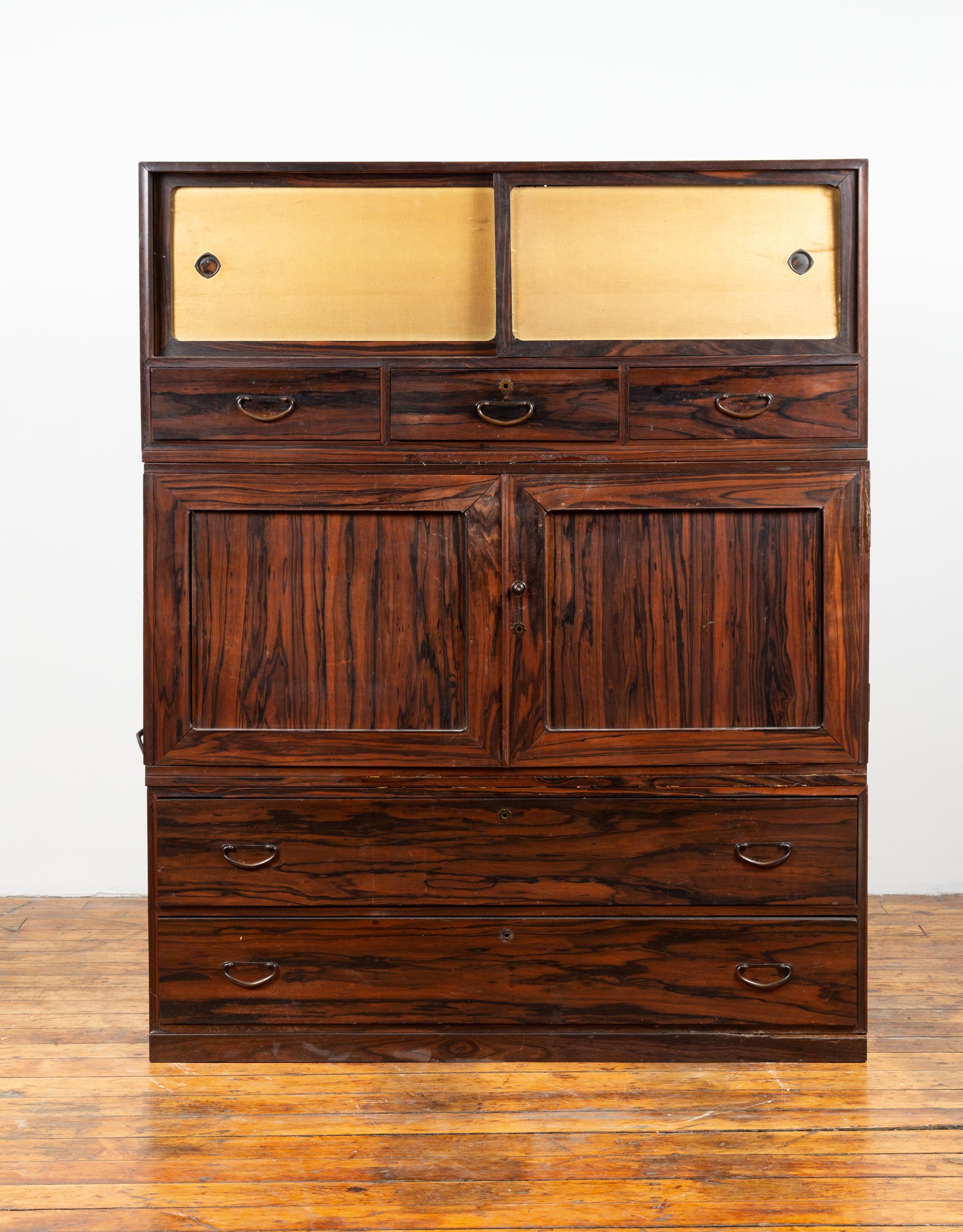 An Japanese mulberry wood kimono cabinet from the 20th century, with sliding doors and drawers. Born in Japan during the 20th century, this exquisite cabinet charms us with its richly grained mulberry wood and convenient features. Presenting an