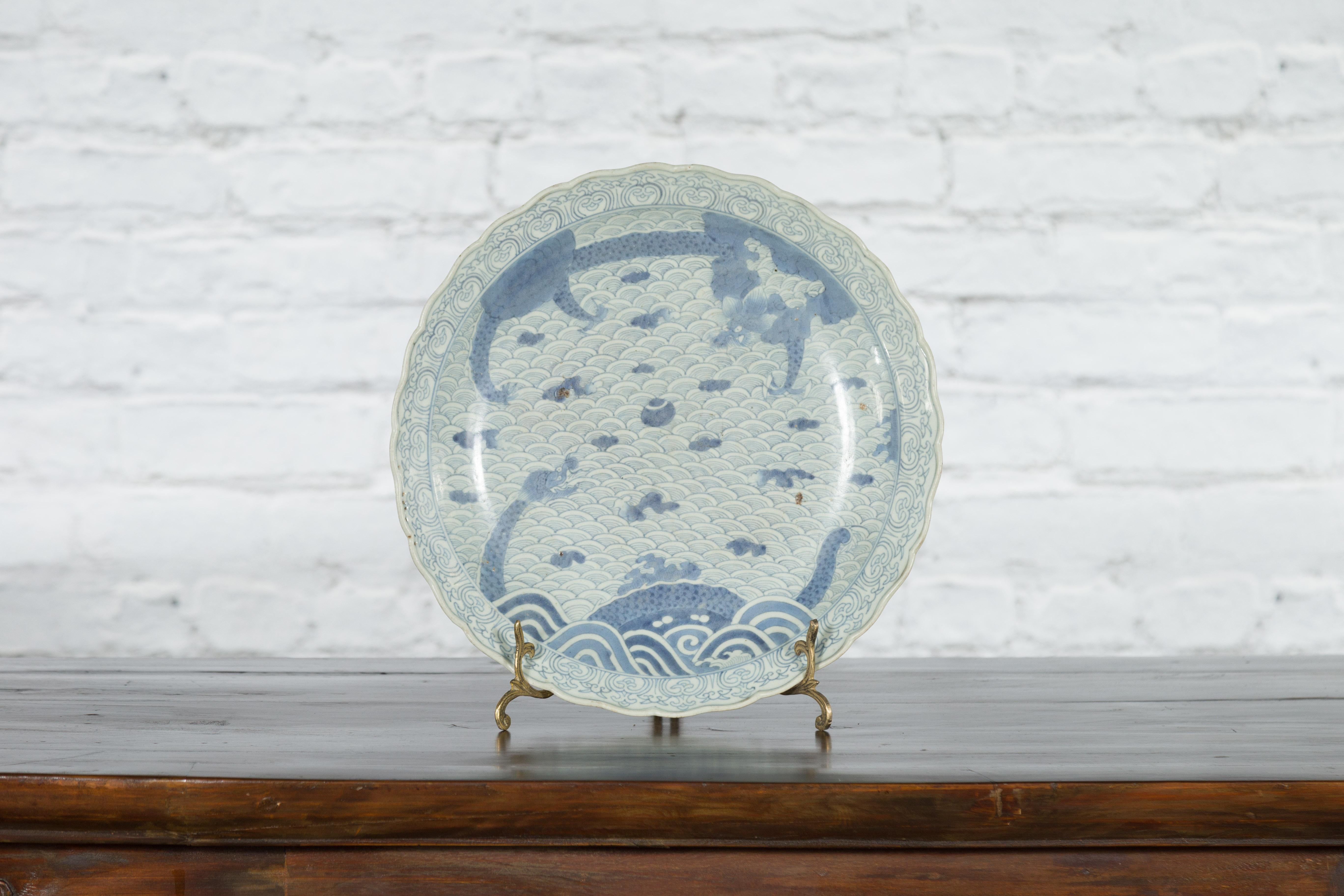 A Japanese porcelain plate from the 19th century, with hand-painted blue and white dragons in clouds décor. Created in Japan during the 19th century, this porcelain plate features a delicate blue and white décor depicting an artistic composition