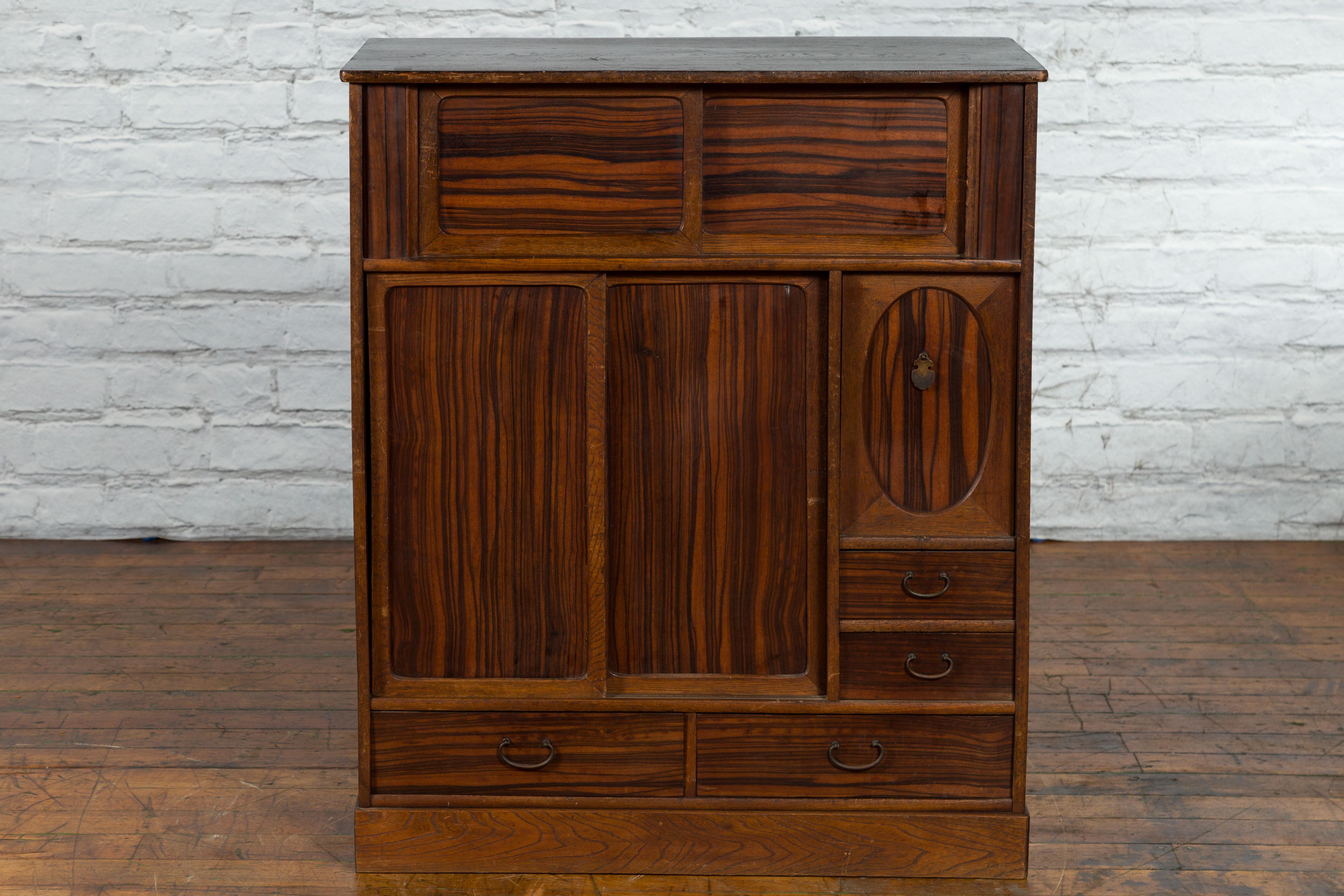 An antique Japanese zebra wood cabinet from the 19th century with four drawers, storage compartments and sliding doors. Created in Japan during the 19th century, this cabinet features a linear silhouette perfectly complimented by a zebra wood