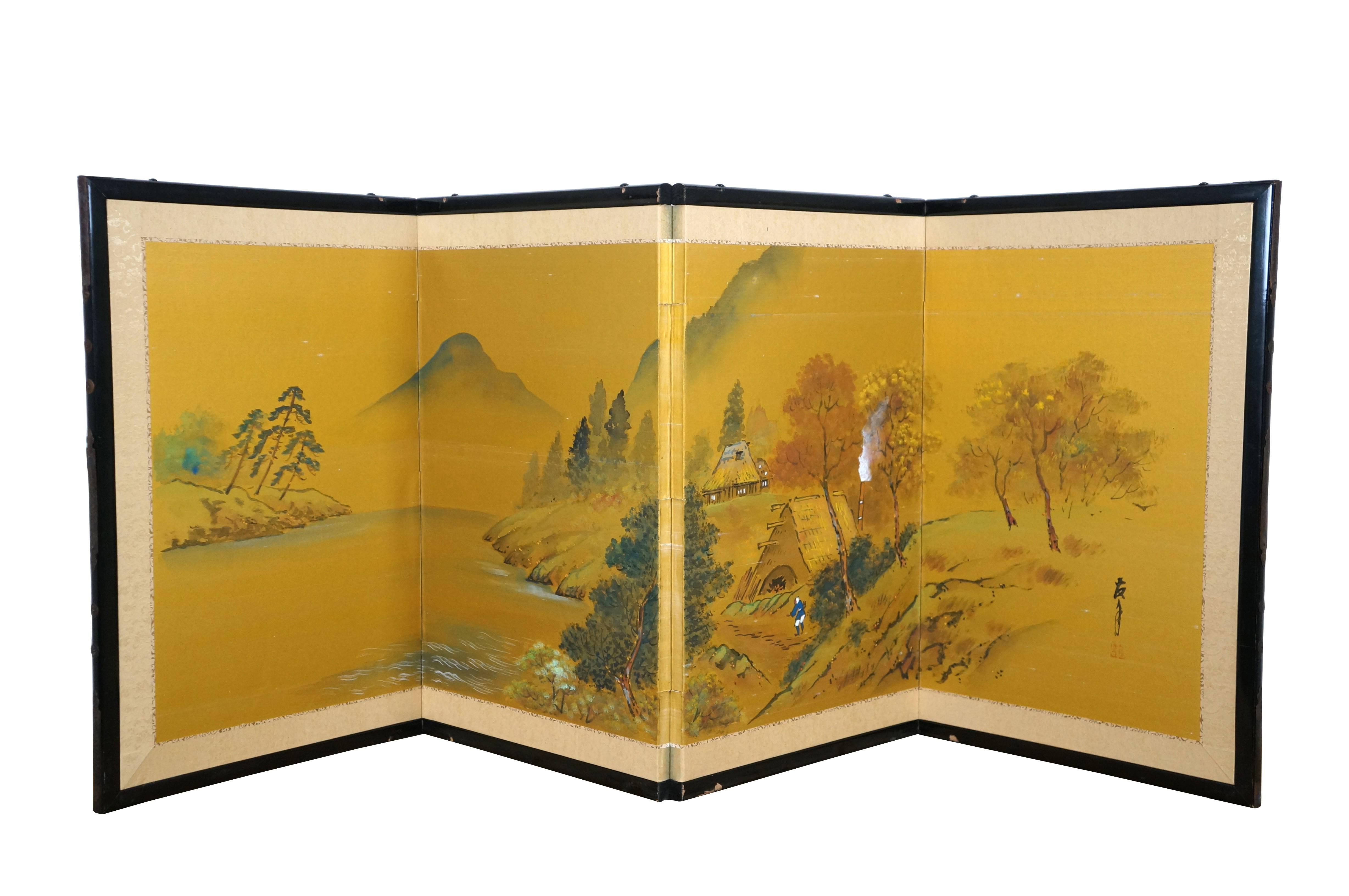 Mid to late 20th century Japanese byobu / folding screen - four black lacquer framed panels holding a hand painted golden landscape on silk, showing a pair of peasant cottages beside a lake, surrounded by mountains and countryside. Signed on right