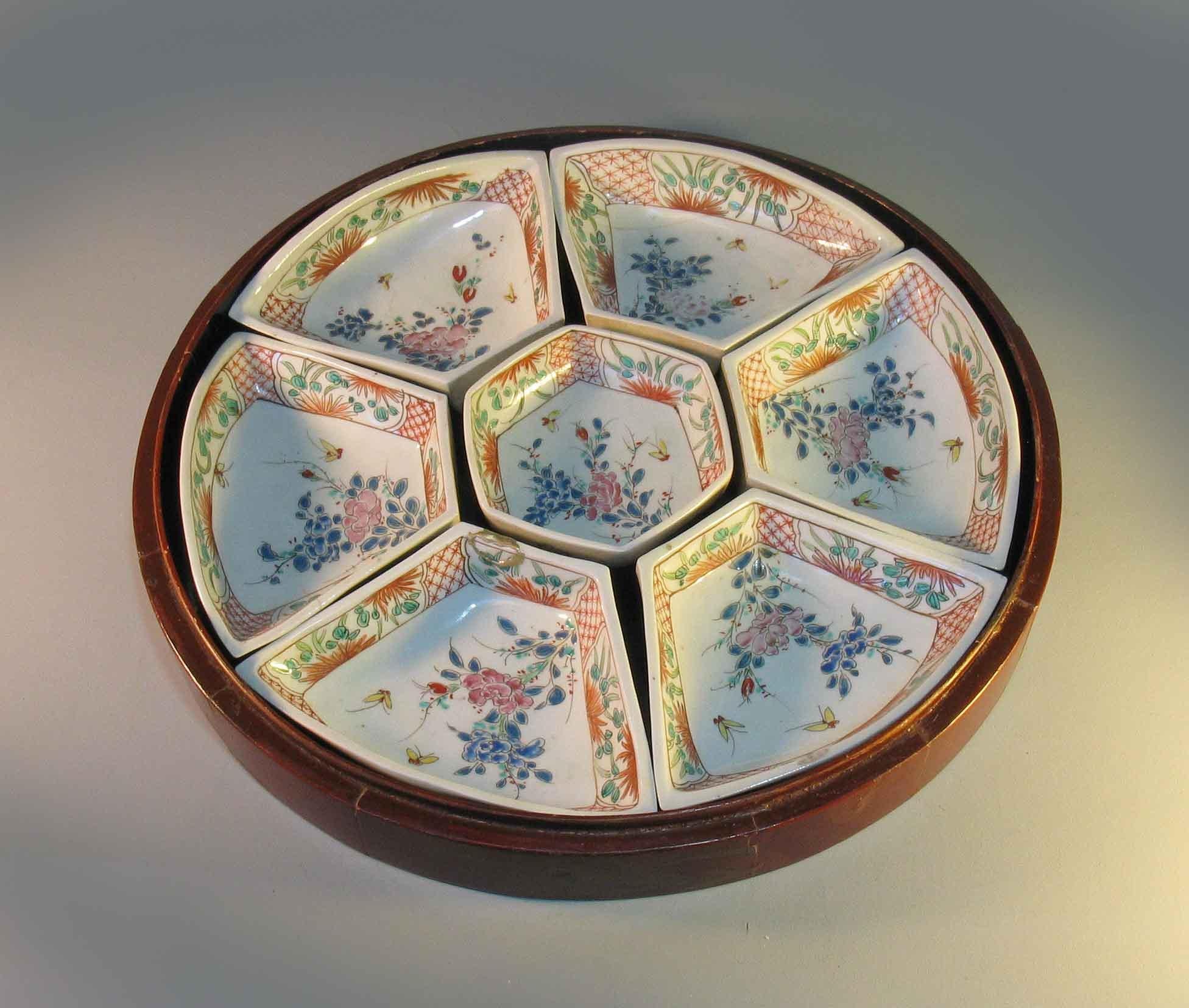 Ensemble de sept sucreries japonaises Arita et boîte en laque assortie, période Meiji (1880-1890). Composé d'un plat central hexagonal et de six plats extérieurs en forme d'éventail, chacun peint dans la palette Kakiemon d'émaux rouge fer, vert,