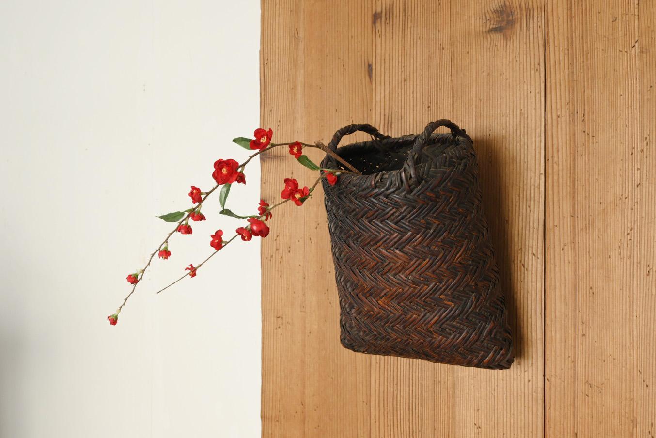 This is a woven bamboo basket made in Japan from the Meiji to Taisho periods (1868-1920).
I don't know if the baskets actually used by farmers were repurposed as flower vases, or if they were originally made for arranging flowers, but it is a design