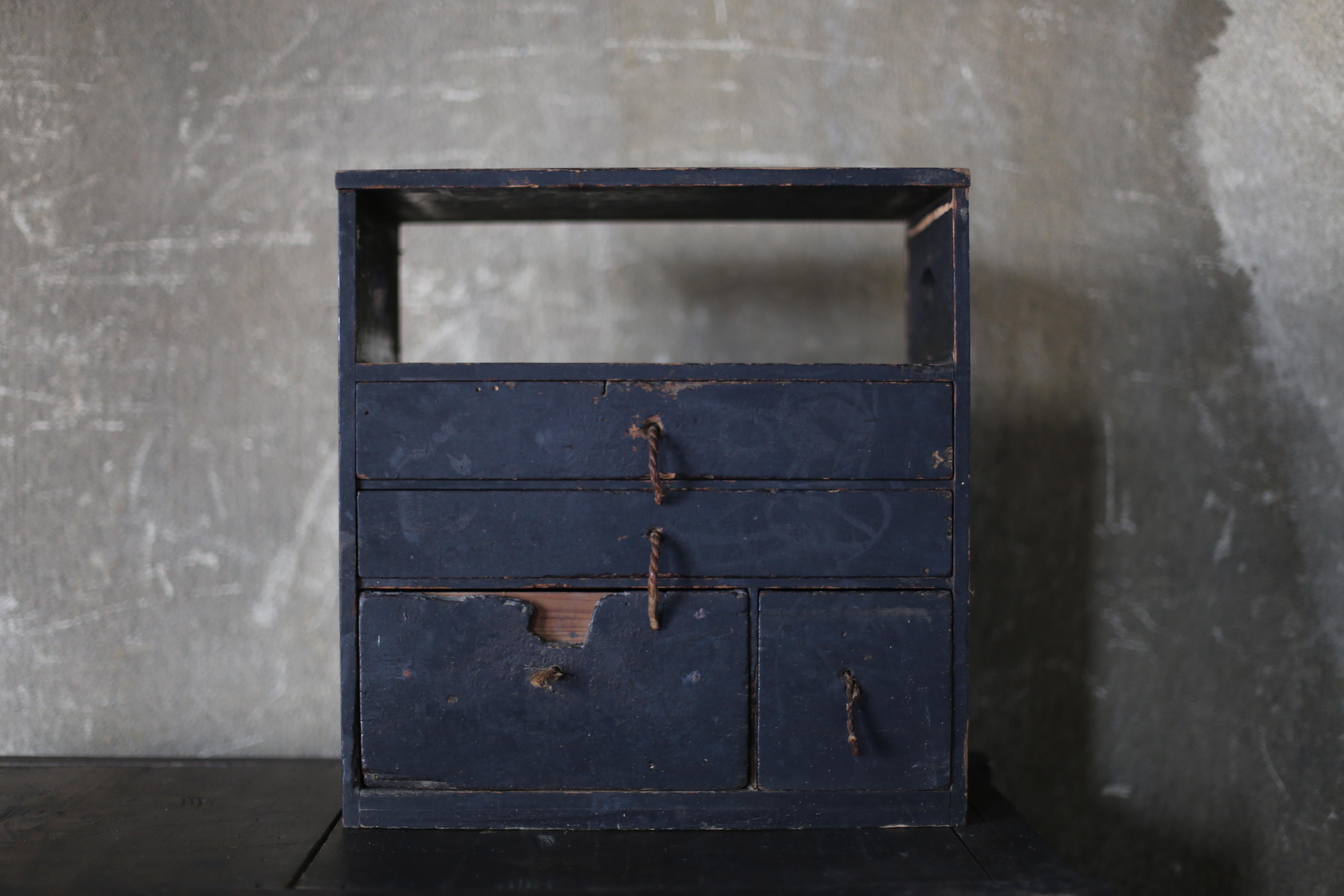 This is a very old black-lacquered drawer storage unit made in Japan.
The original handles still have old ropes attached, suggesting it is very old.
It is thought to date from the Edo or Meiji period.
It is made of cedar.

The design is simple and